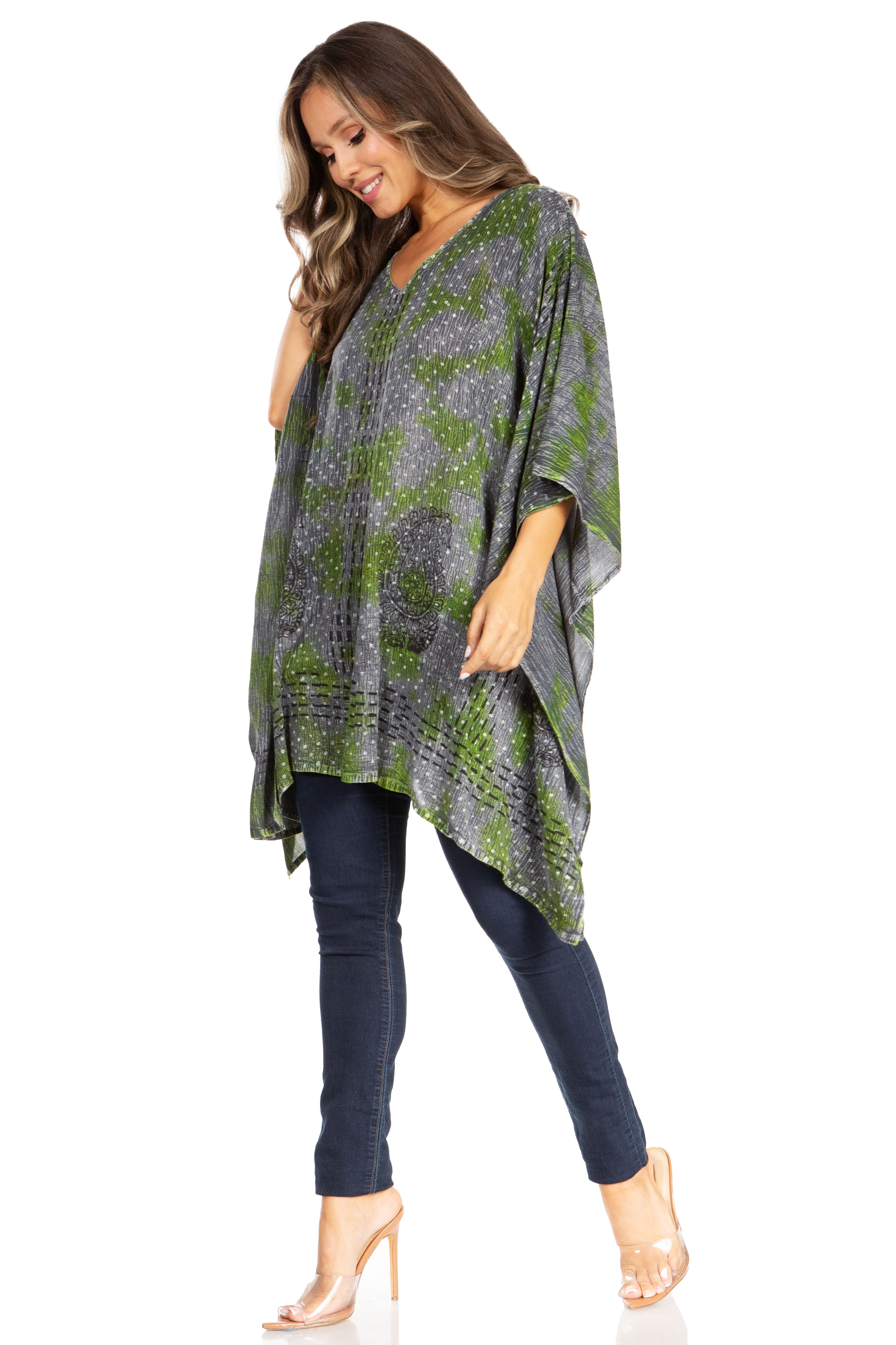 Woman wearing a patterned poncho over a dark outfit on a white background