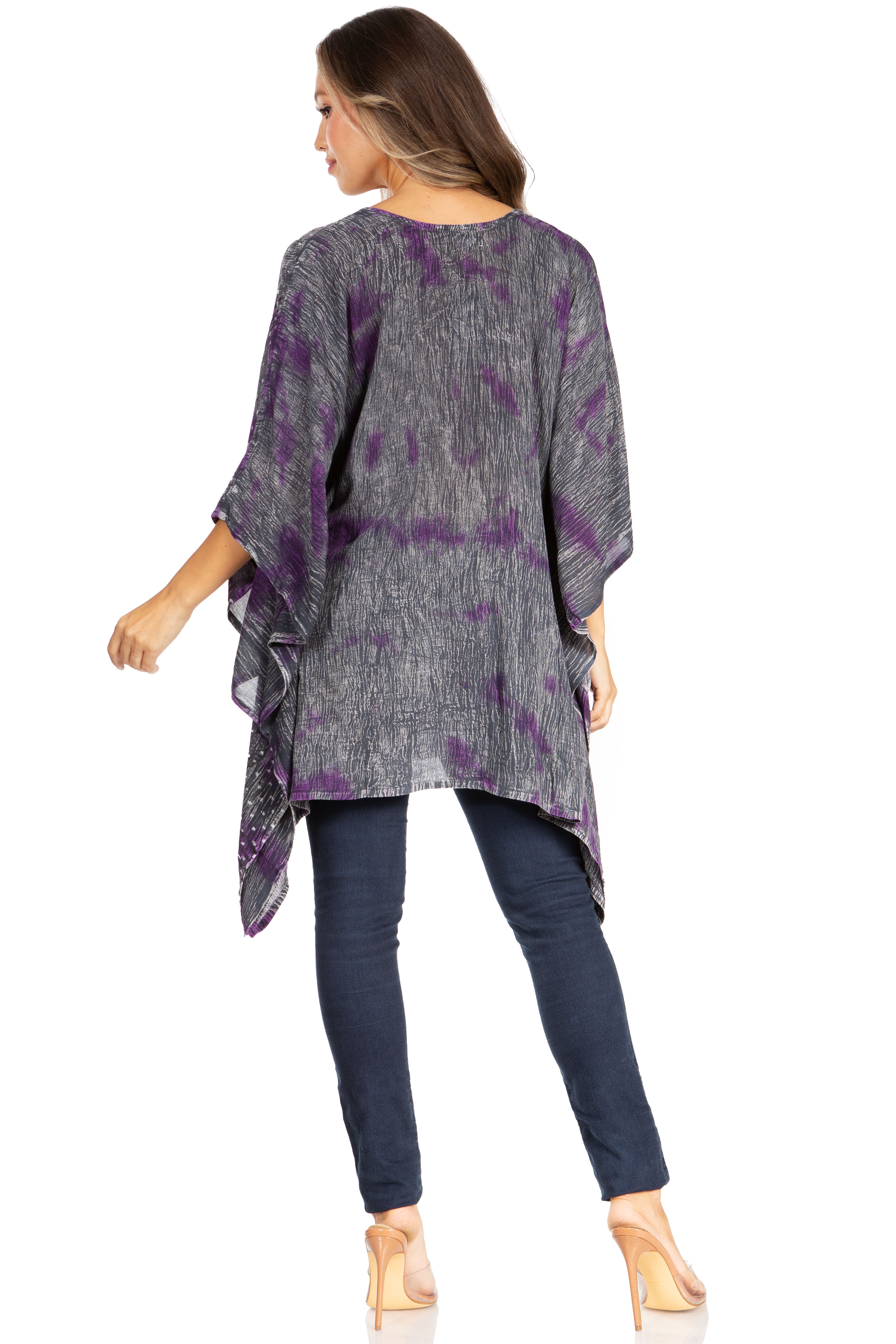 Woman wearing a gray and purple patterned top with navy pants on a white background