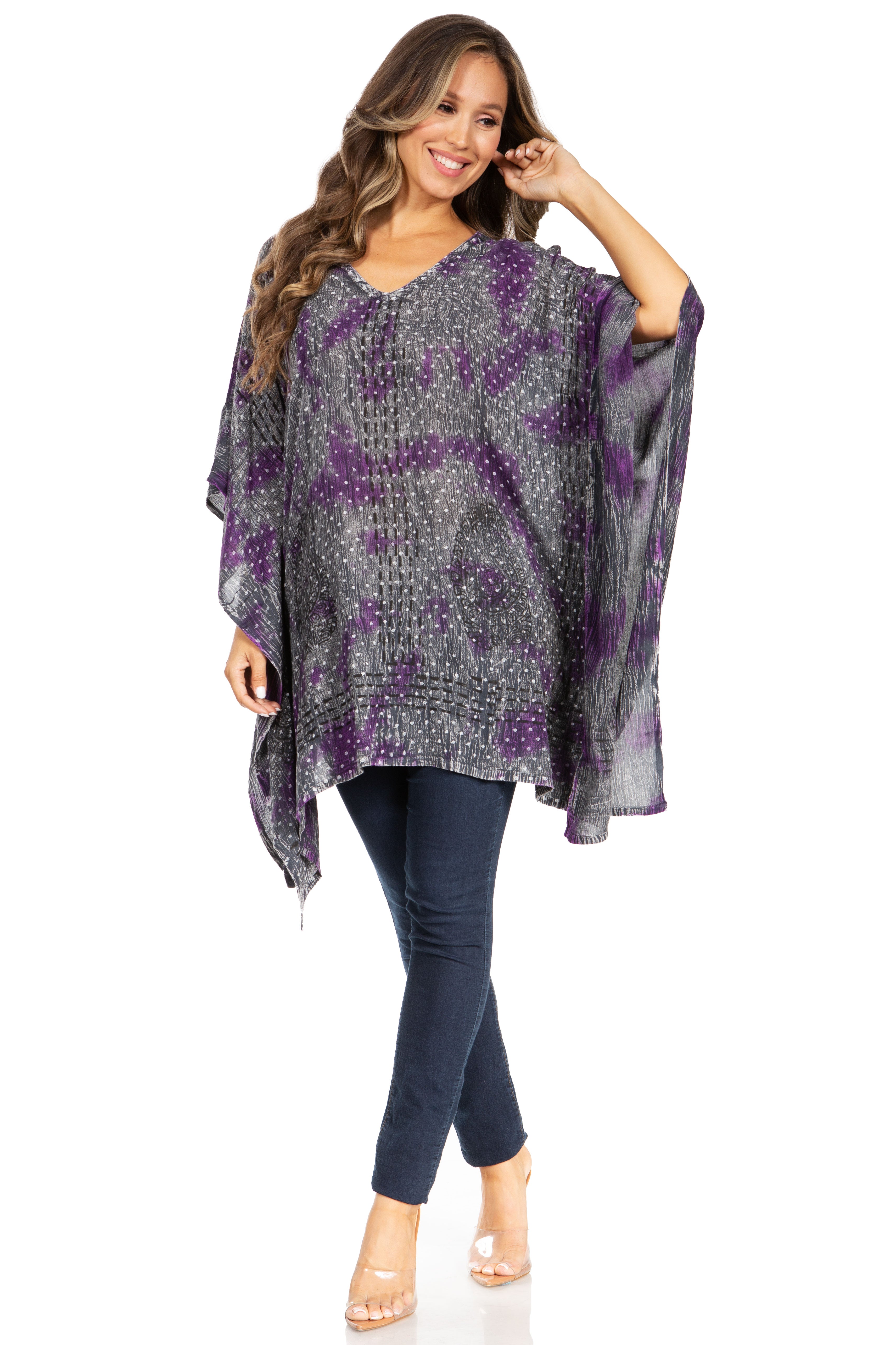 Woman wearing a patterned poncho and dark pants on a white background