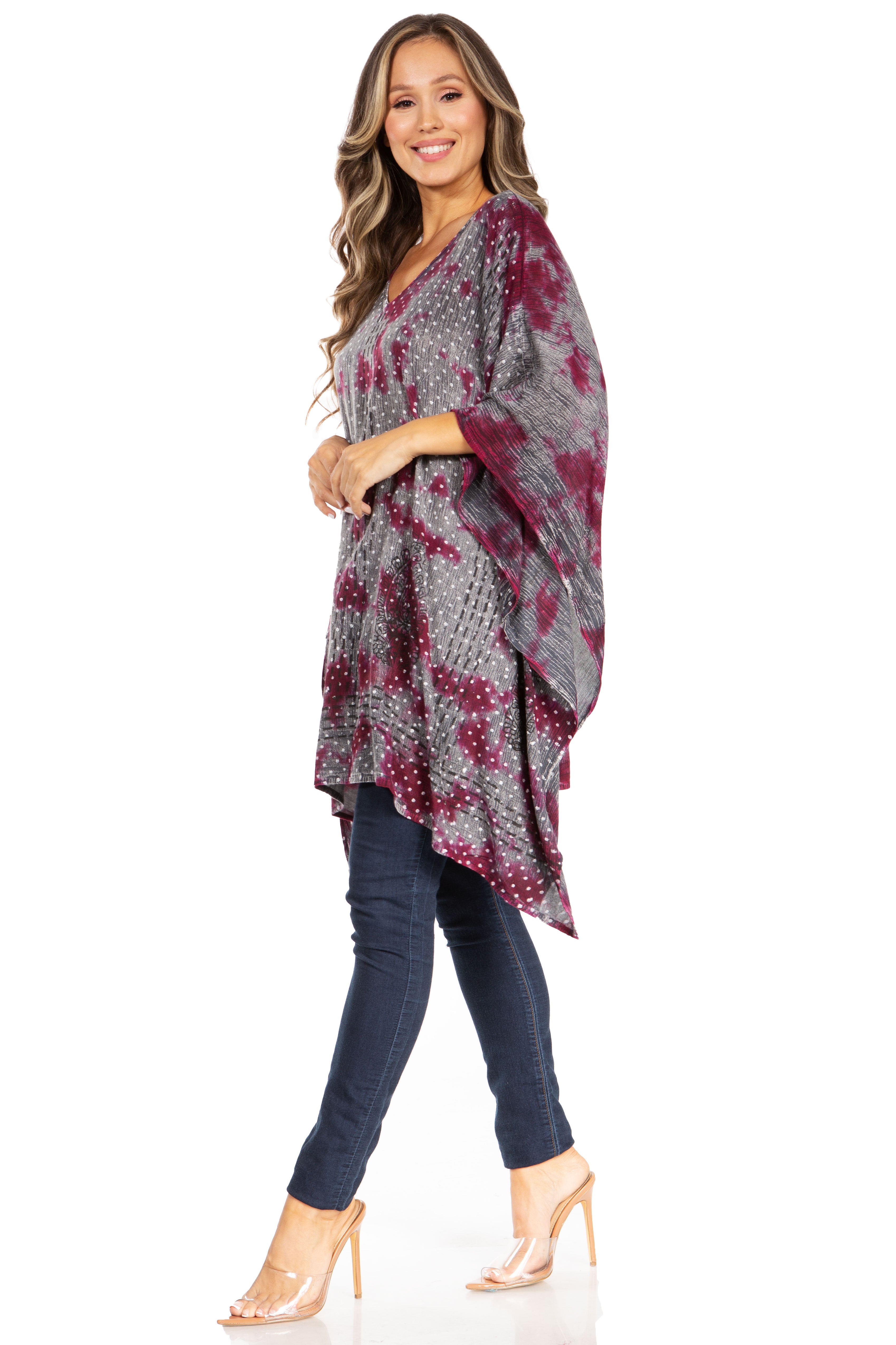 Woman wearing a patterned poncho over a dark outfit on a white background