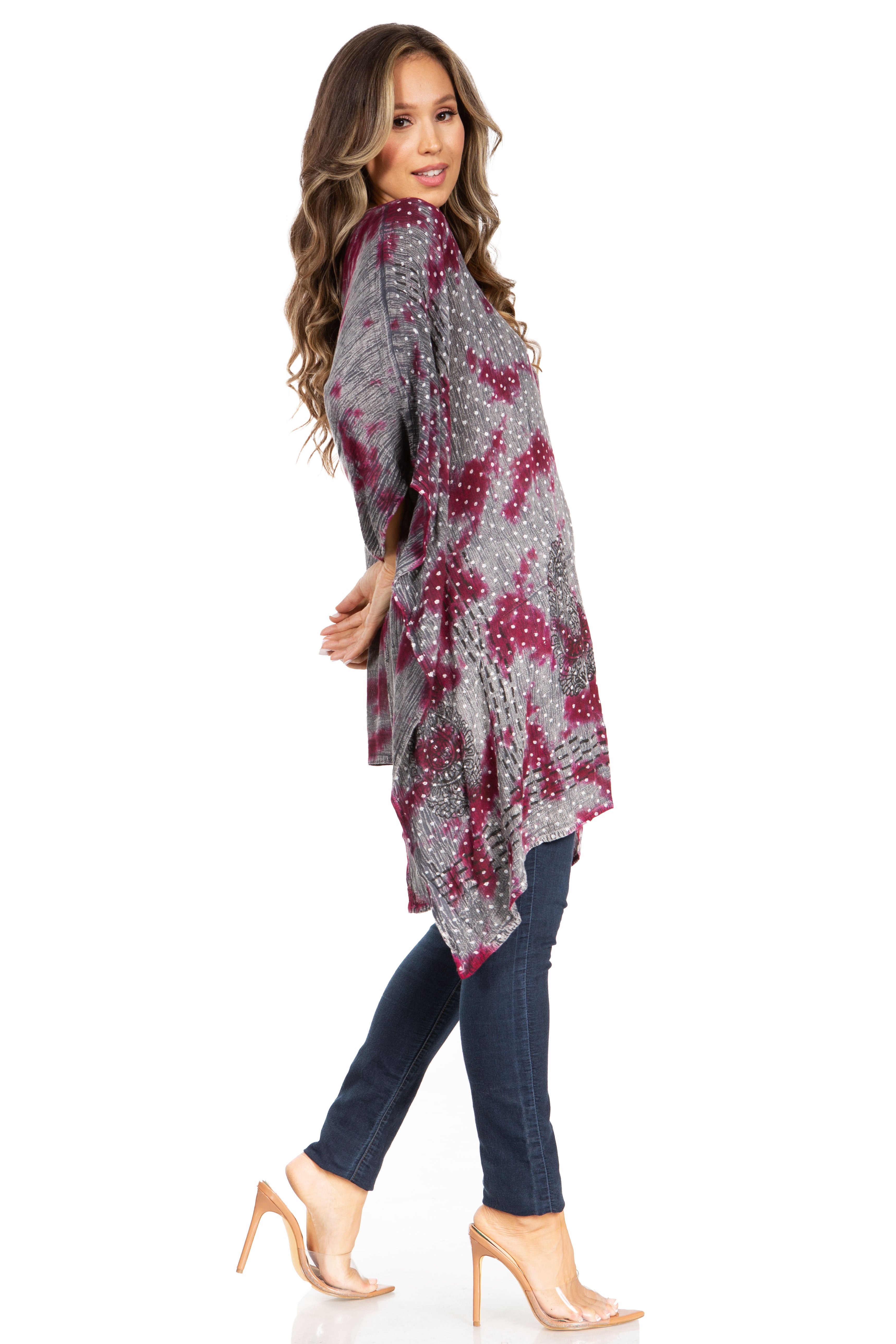 Woman wearing a patterned gray and red top with blue jeans on a white background