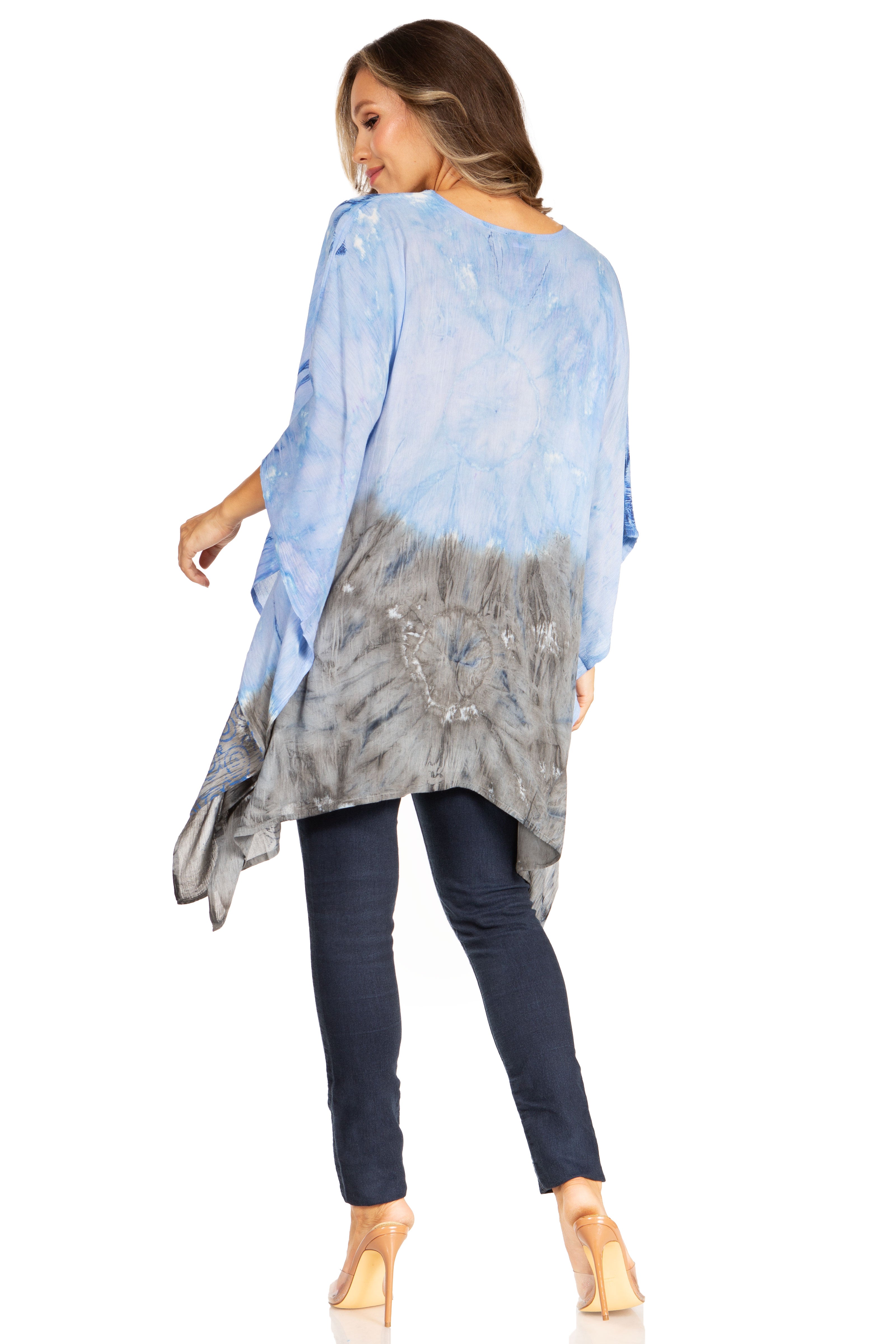 Woman wearing a blue and gray tie-dye top with dark jeans on a white background