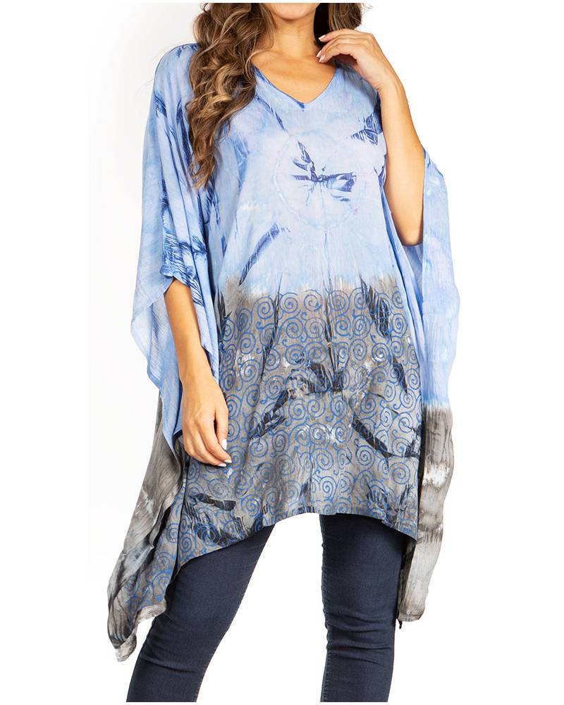 Woman wearing a blue patterned poncho over a plain top and pants on a white background