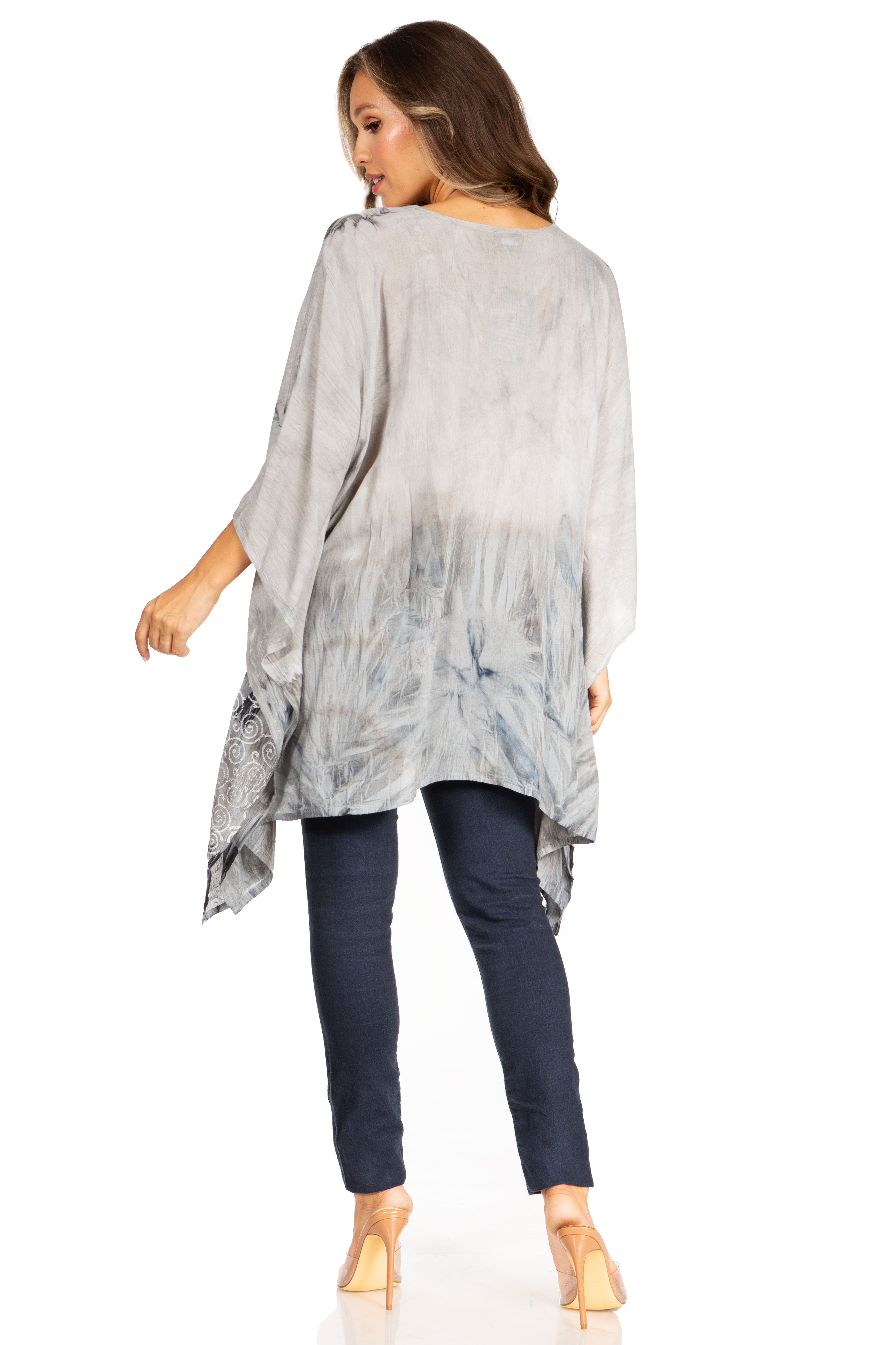 Woman wearing a light gray tie-dye top and dark blue pants on a white background