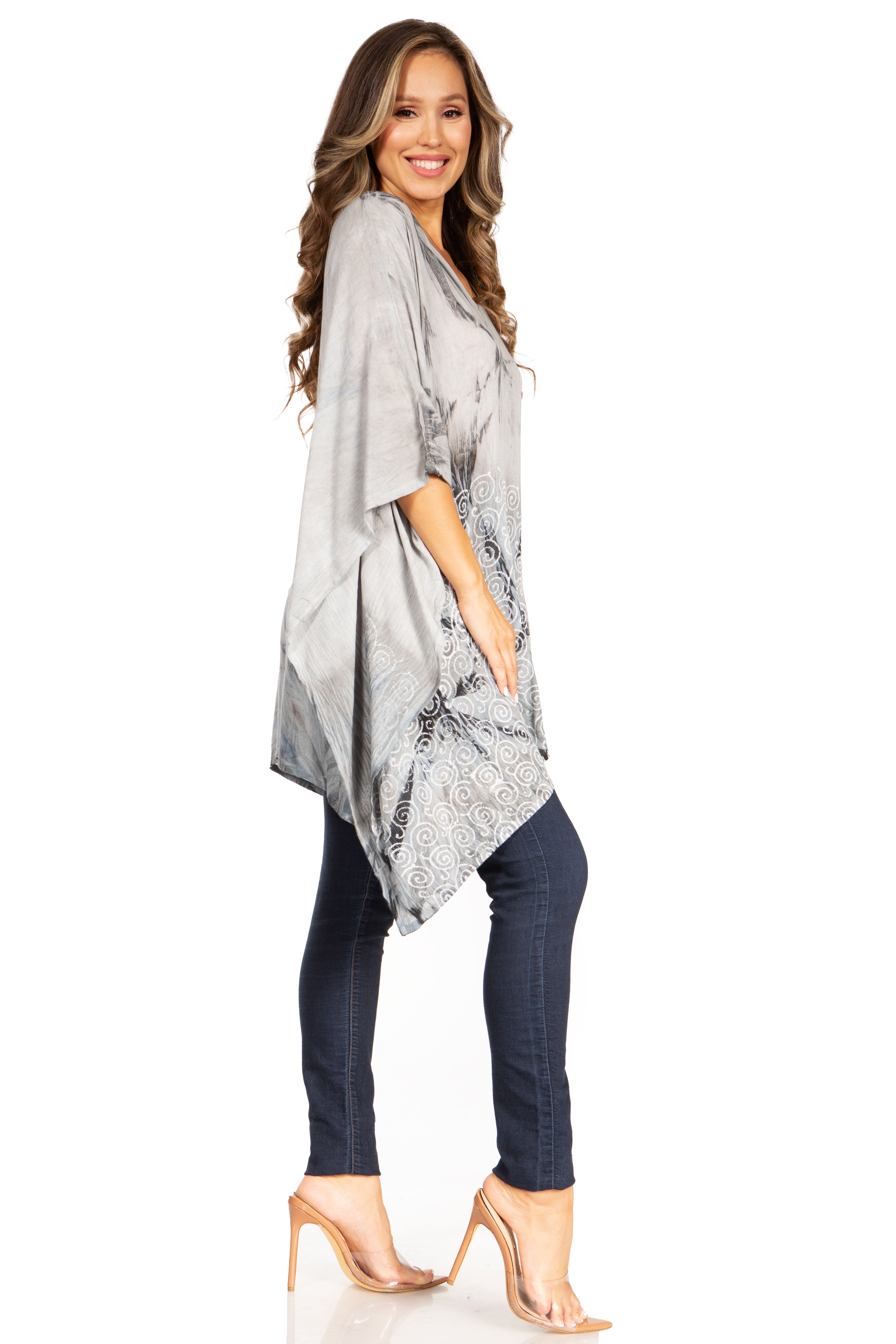 Woman wearing a gray patterned kimono-style top and dark jeans on a white background