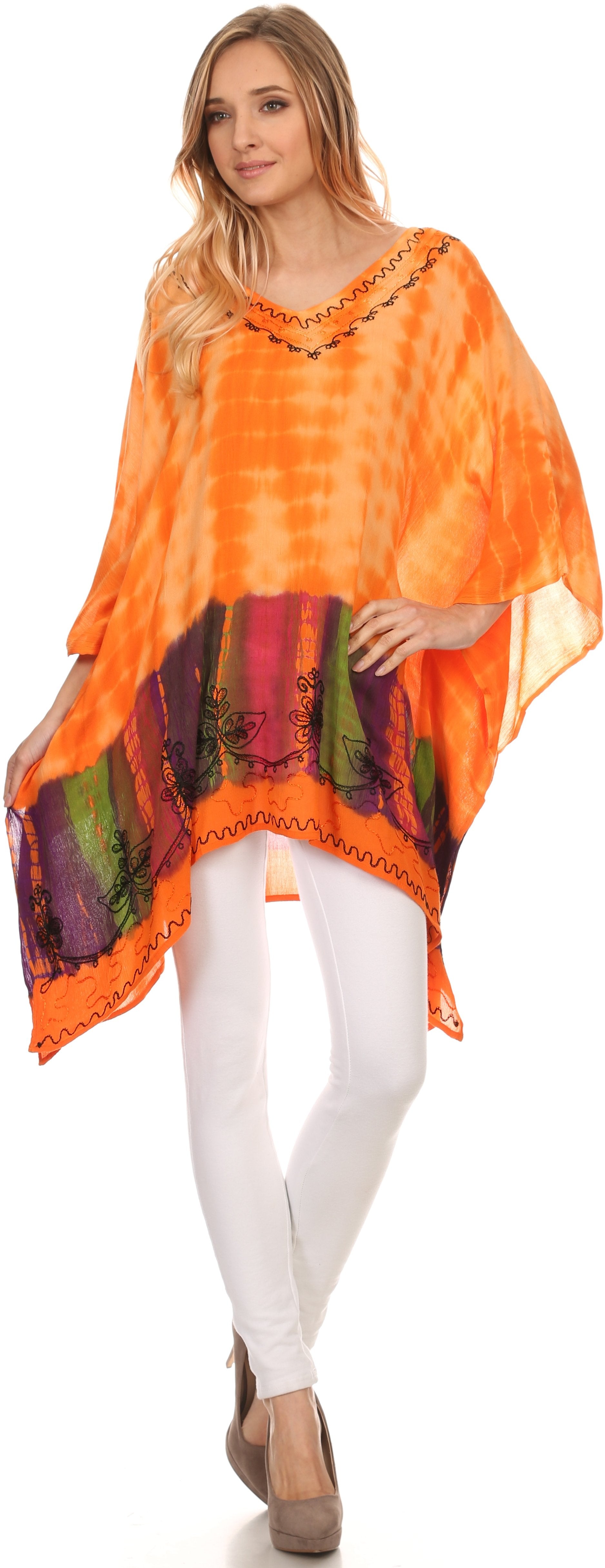 Woman wearing an orange tie-dye poncho over a colorful striped shirt with white pants on a white background