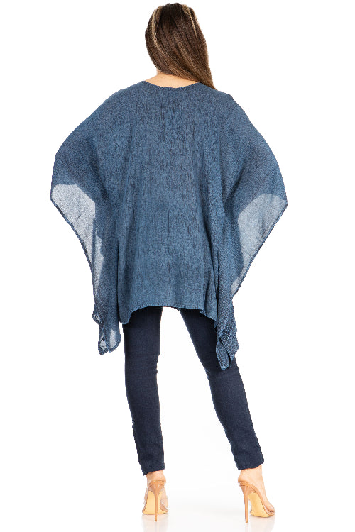 Woman wearing a blue poncho over a dark outfit on a white background