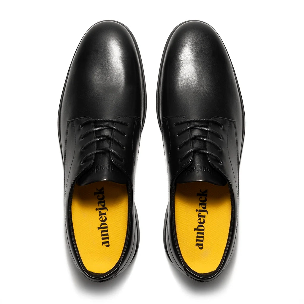 Black leather shoes with yellow soles on a white background