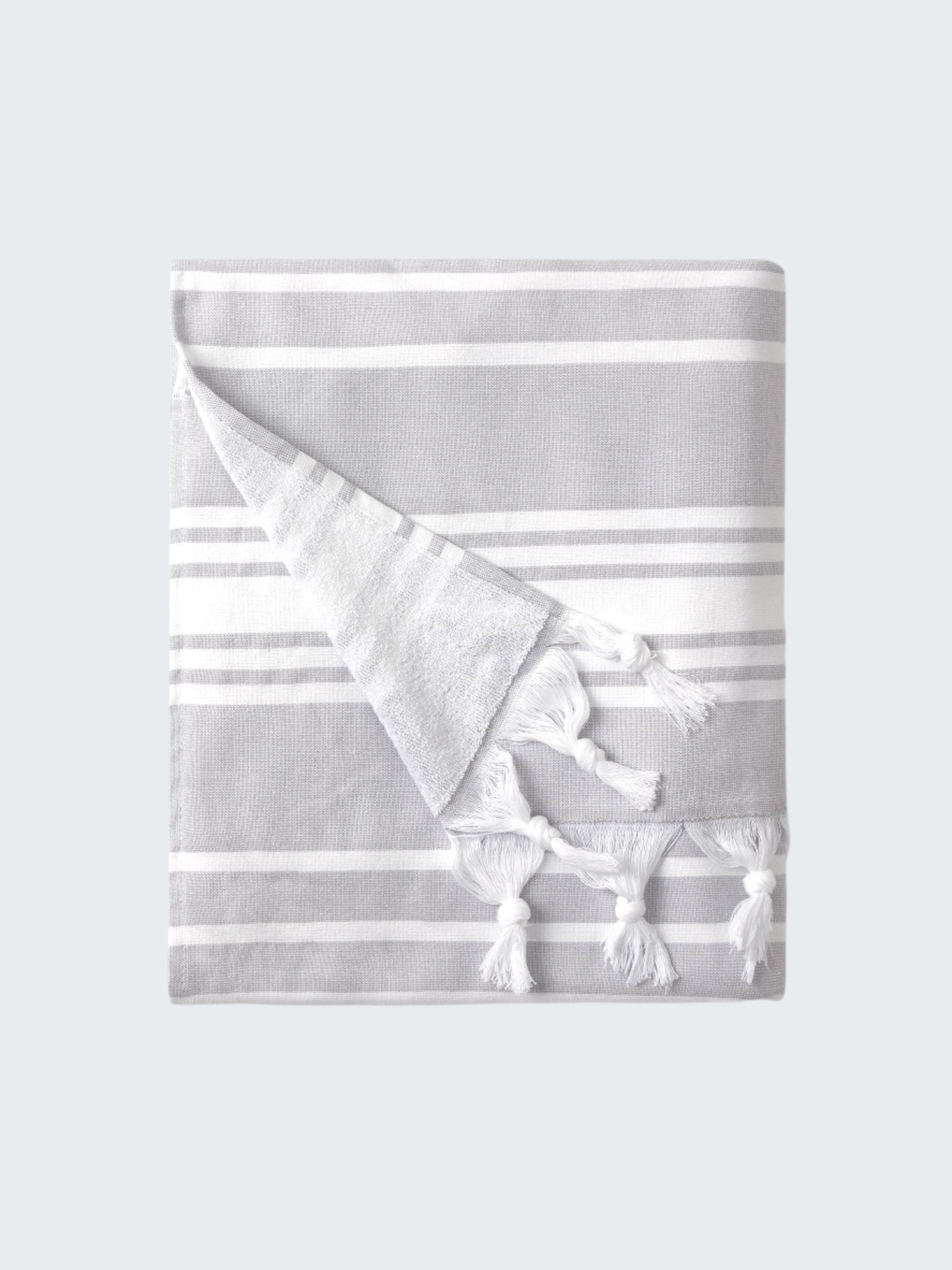 Folded gray and white striped towel with tassels on a white background