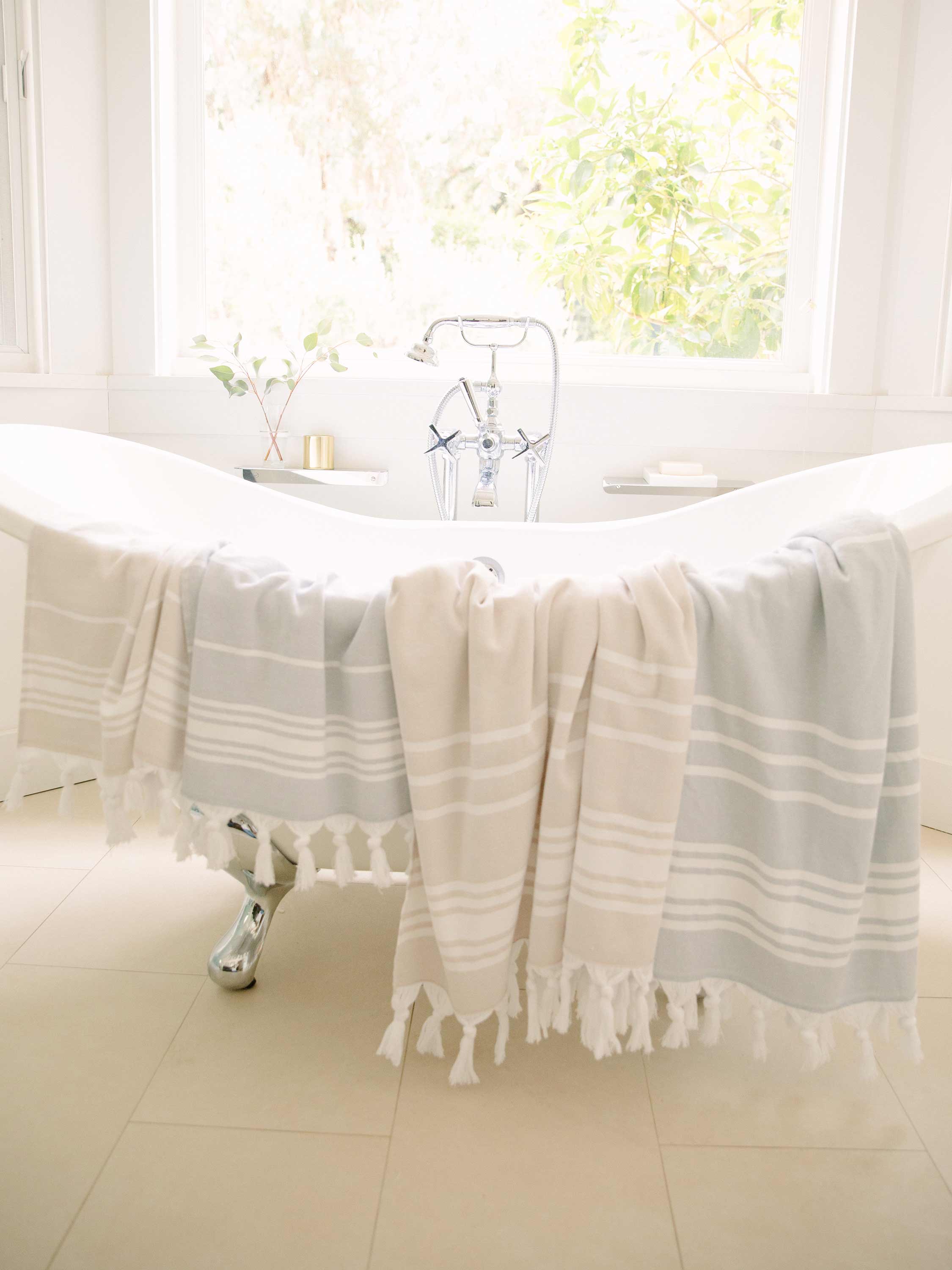 White bathtub with a towel draped over it in a bright bathroom