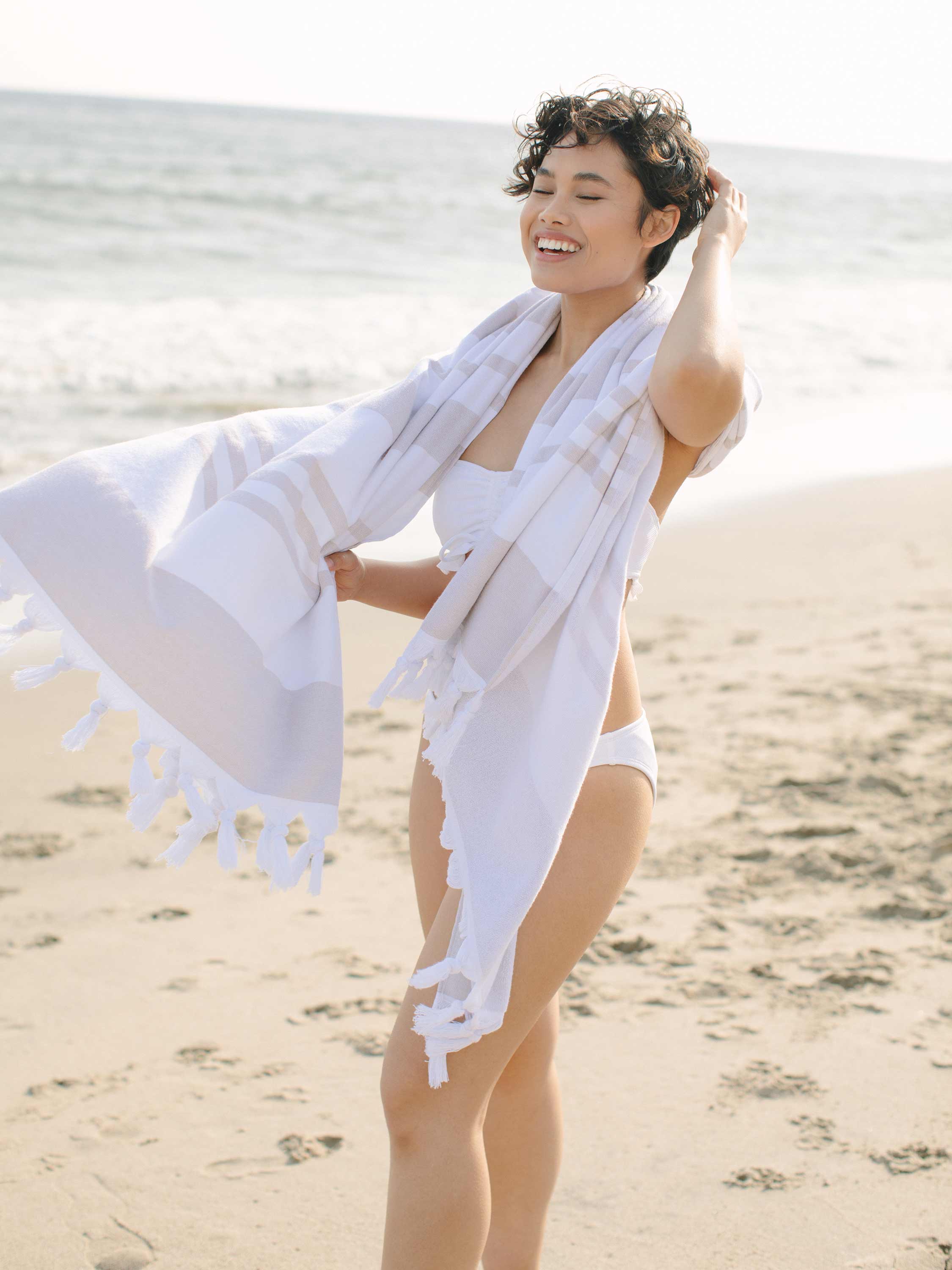 Woman on a beach holding a white towel