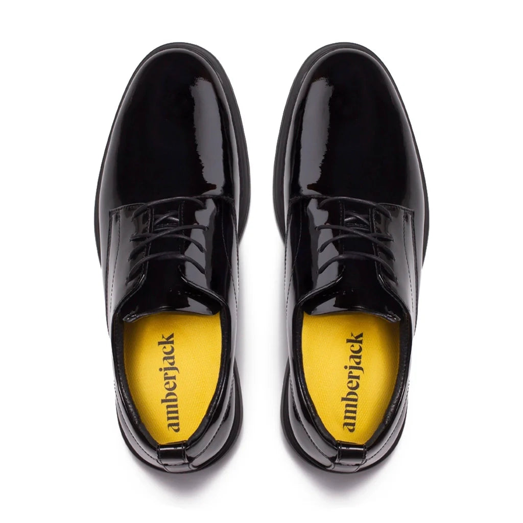 Black patent leather shoes with yellow soles on a white background