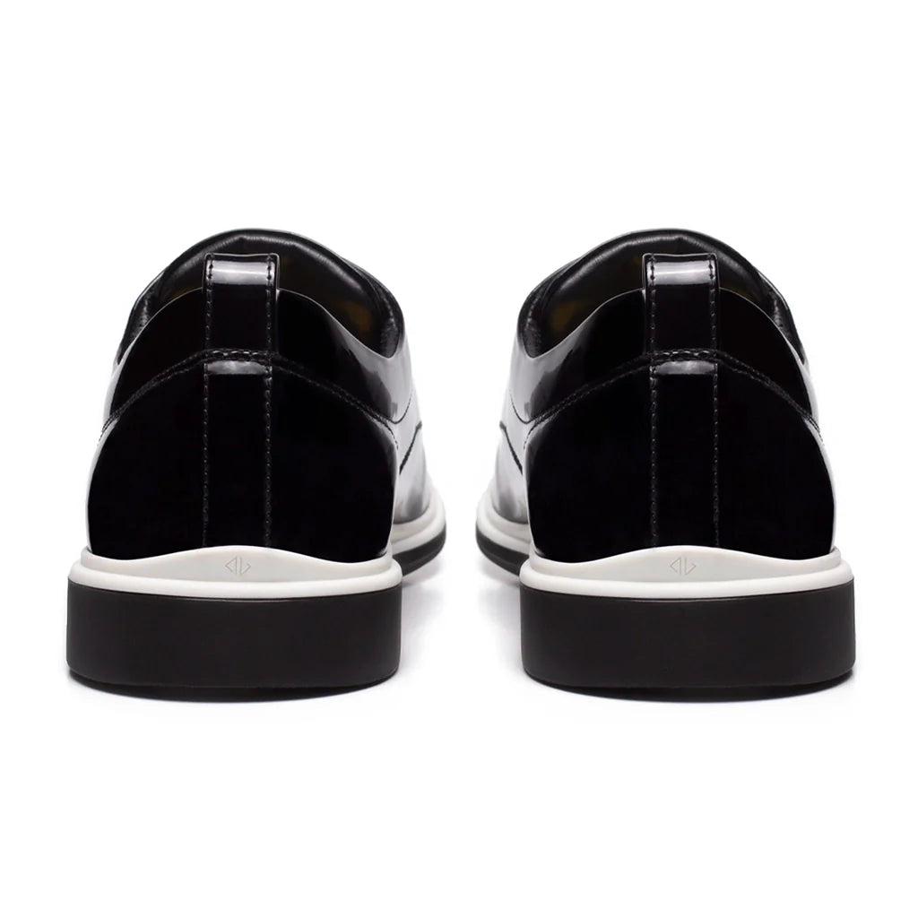 Black patent leather shoes with white soles on a white background
