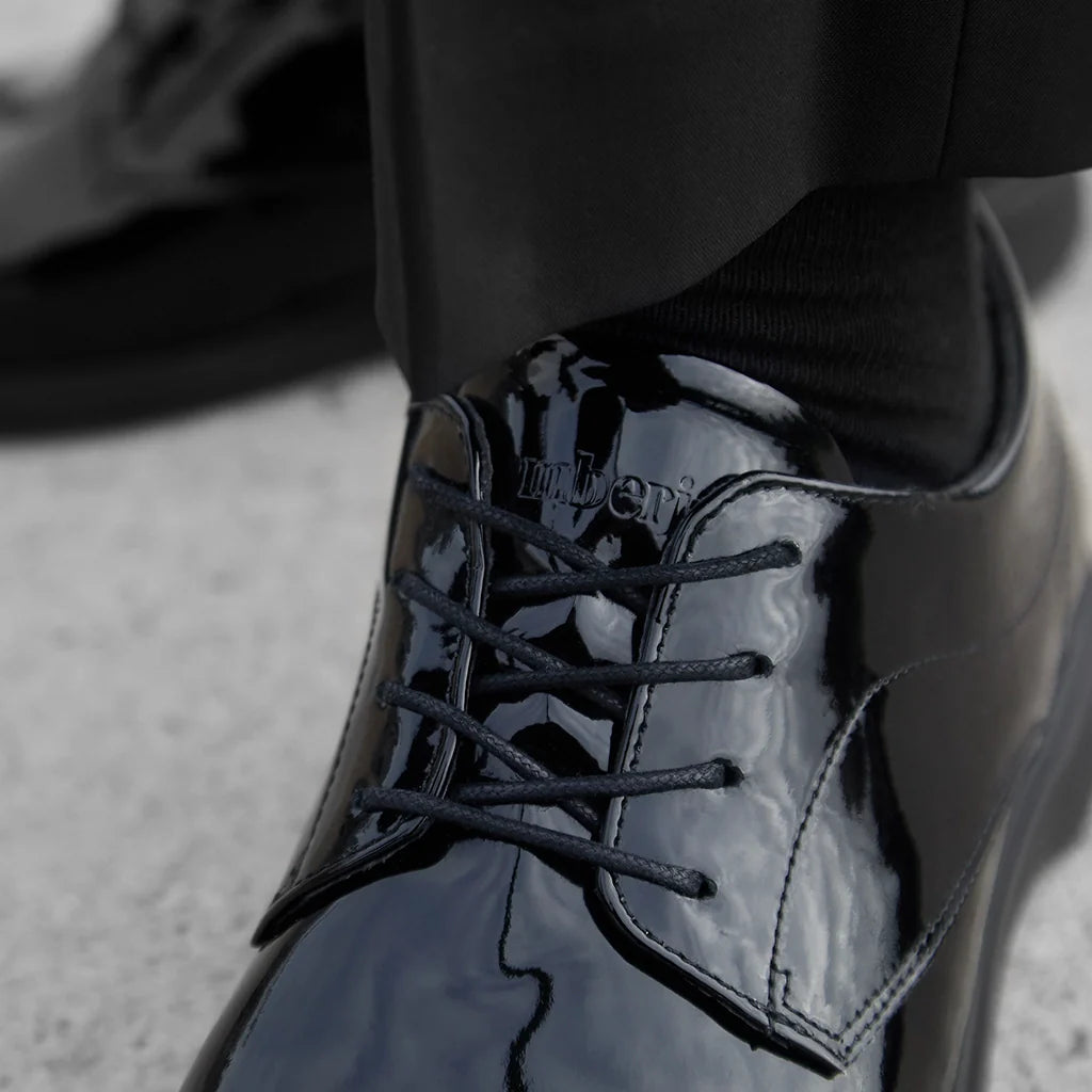 Black patent leather shoe with brand name on a blurred background