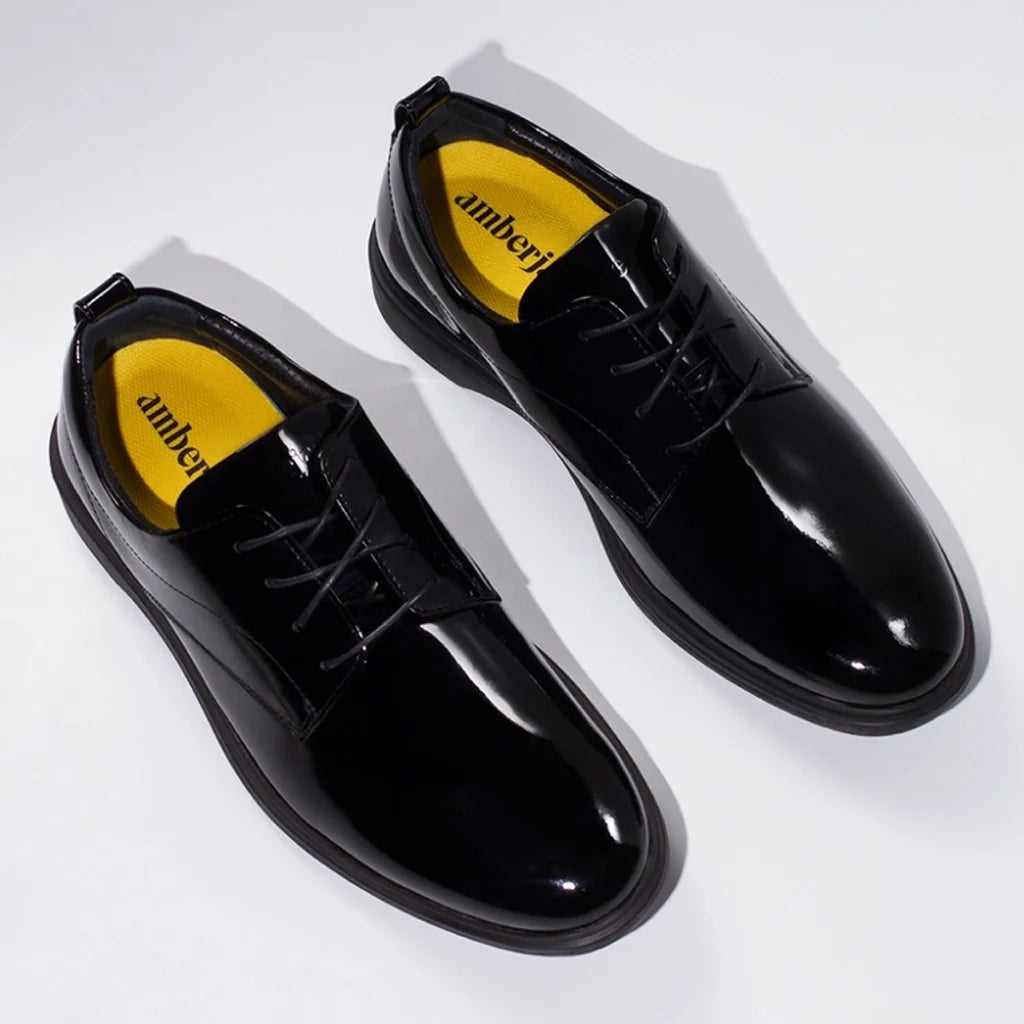 Black shiny dress shoes with yellow soles on a white background