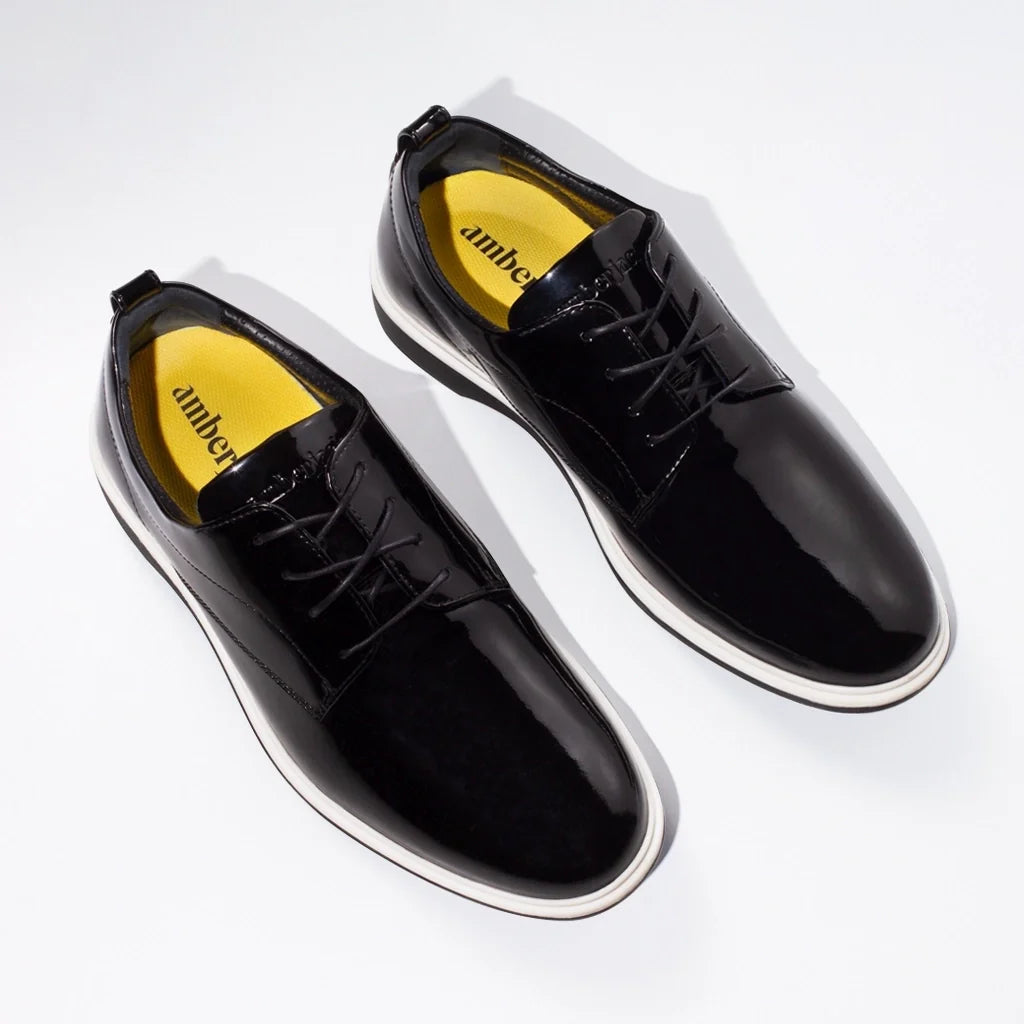 Black shiny dress shoes with yellow lining on a white background