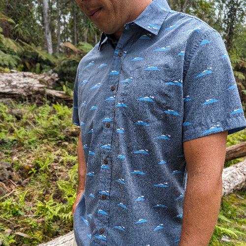 Person wearing a blue patterned shirt in a forest setting