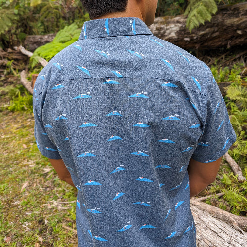 Person wearing a blue patterned shirt in a forest setting