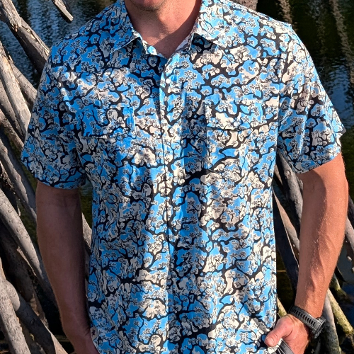 Person wearing a blue and black patterned shirt standing outdoors.