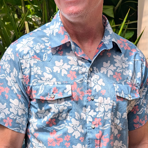 Man wearing a blue floral shirt with plants in the background