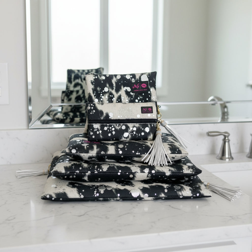 Black and white patterned pouches with tassels and visible branding on a white background