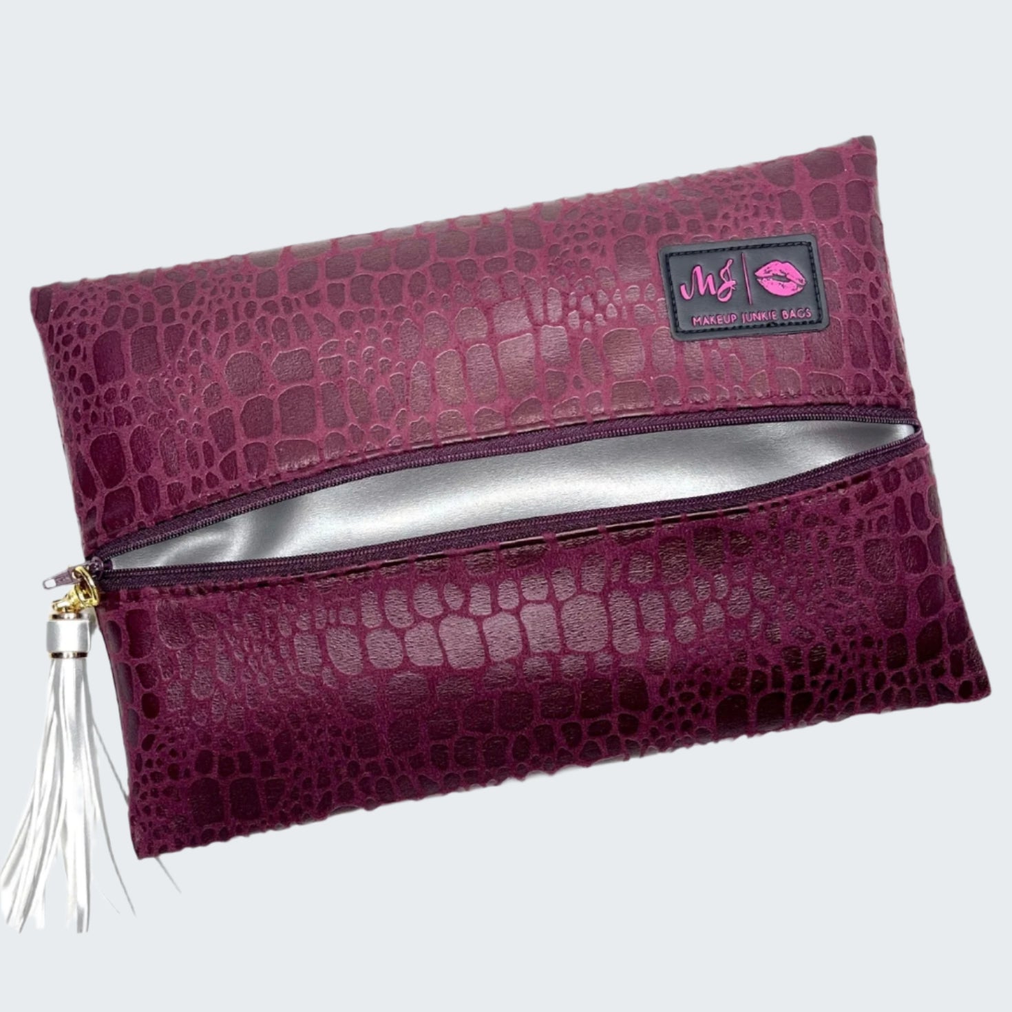 Purple crocodile-patterned clutch bag with a visible brand logo on a white background