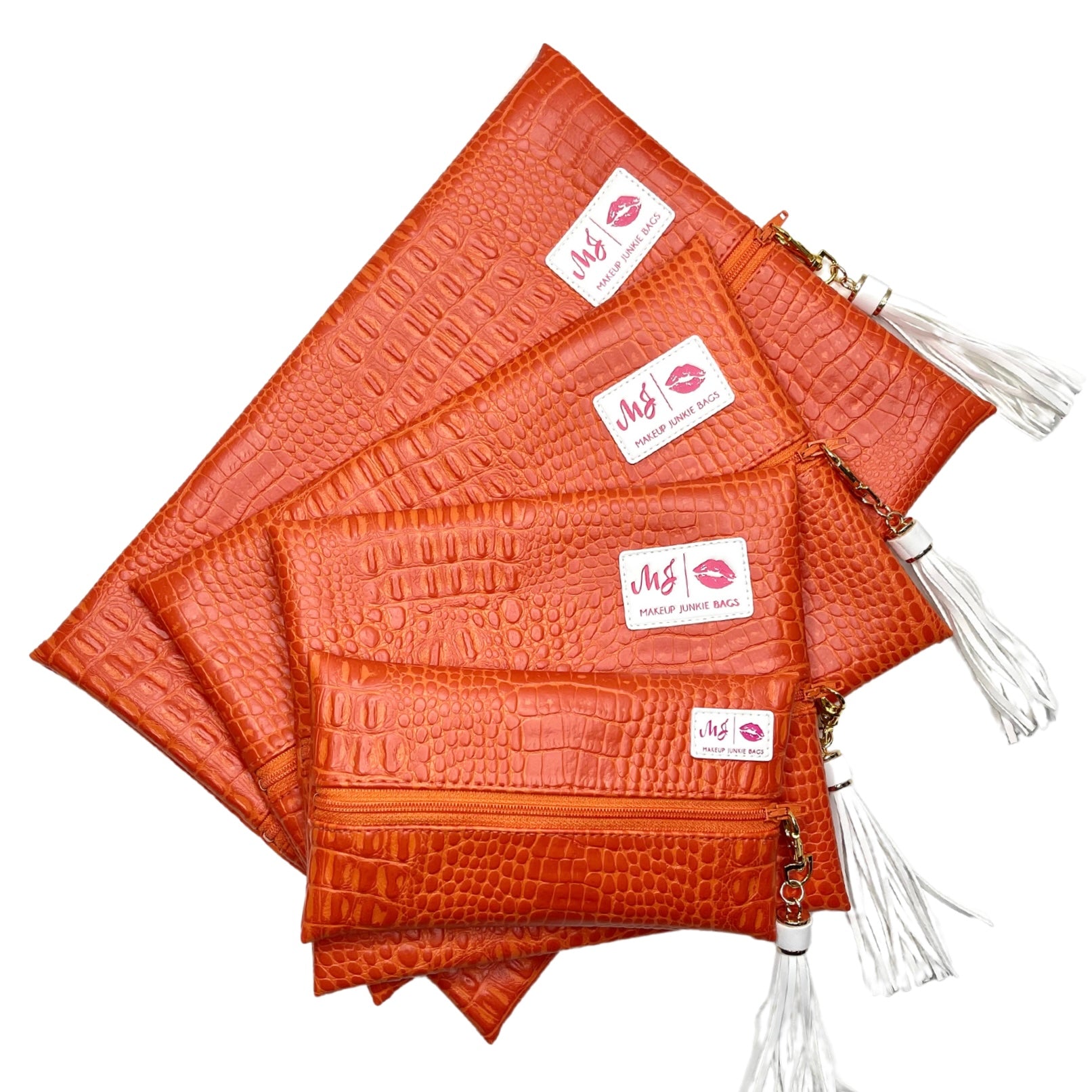 Set of orange crocodile-textured pouches with white tassels on a white background