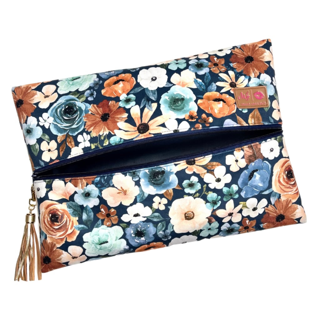 Floral patterned clutch bag with a tassel on a white background