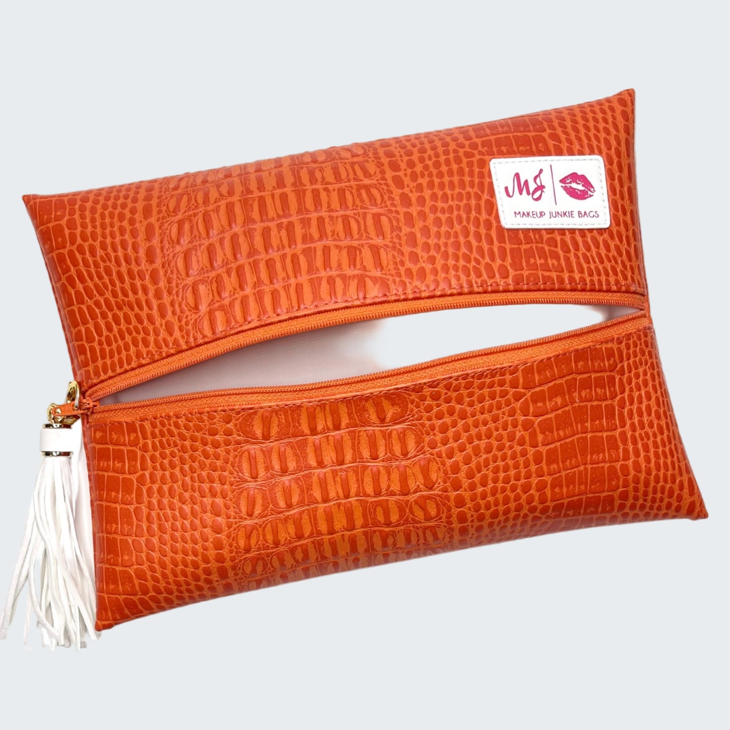 Orange crocodile-textured clutch bag with a visible brand logo on a white background