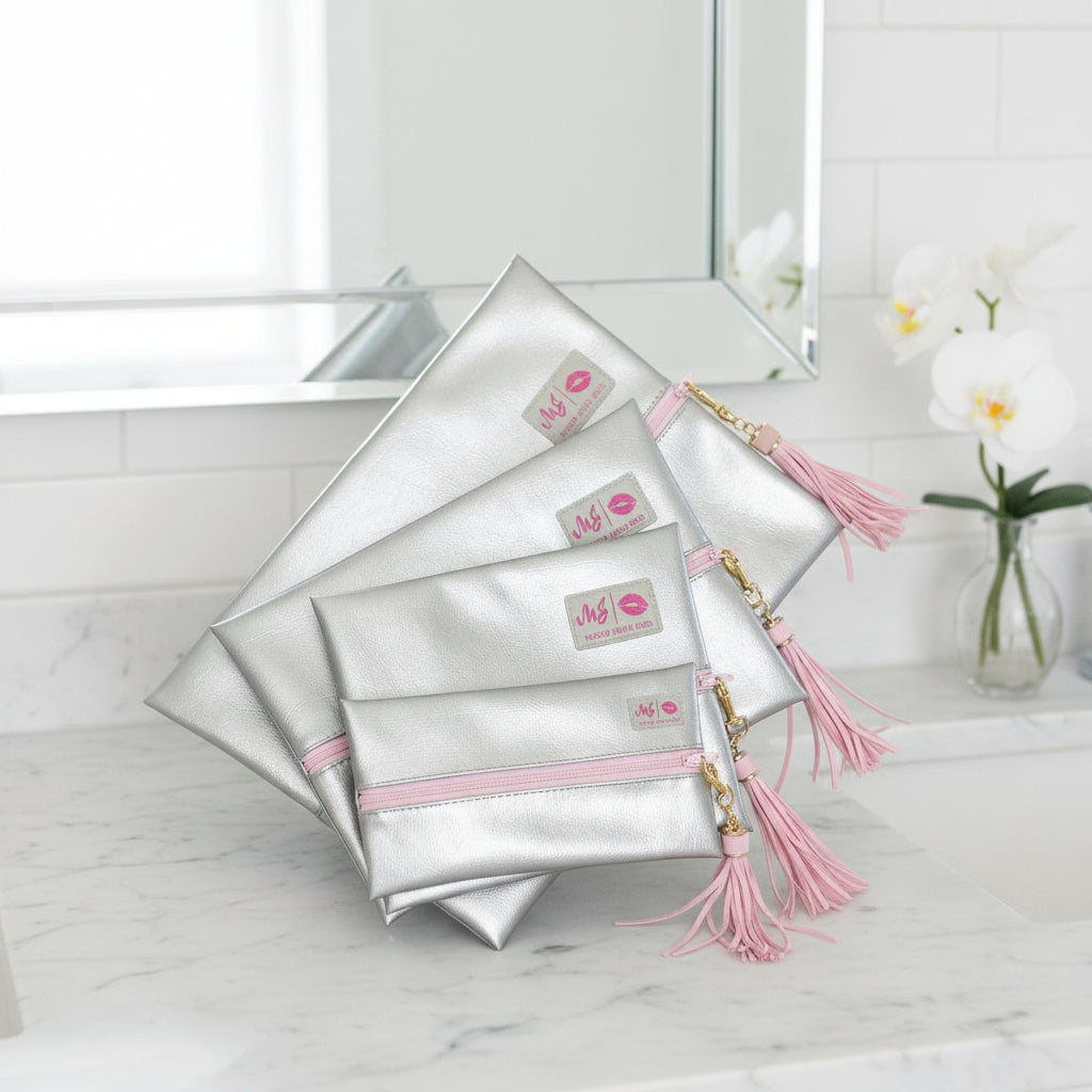 Set of silver pouches with pink accents and tassels on a white background