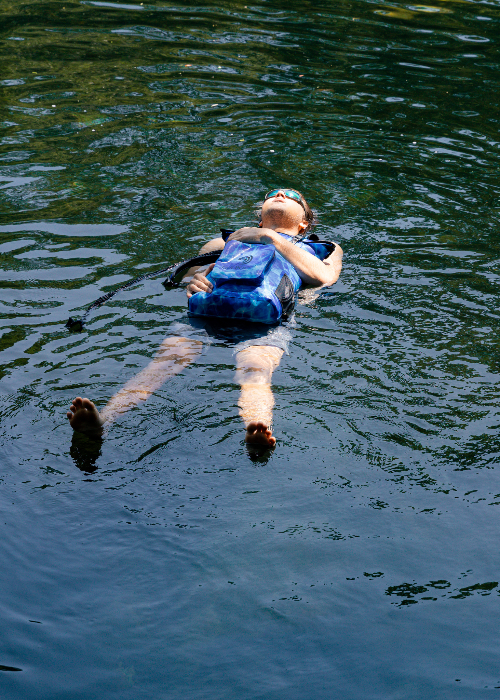 Person floating on water wearing a blue backpack