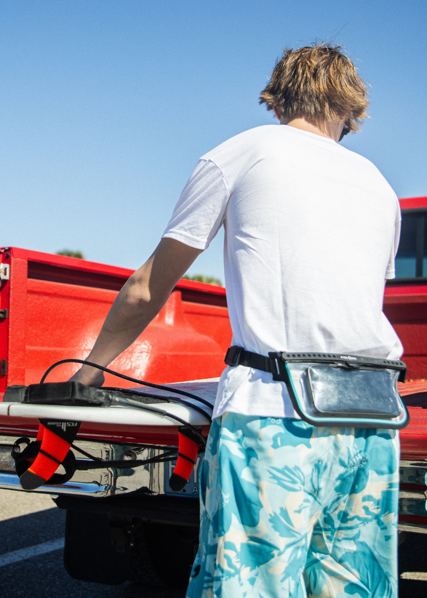 Person with a fanny pack standing next to a red truck