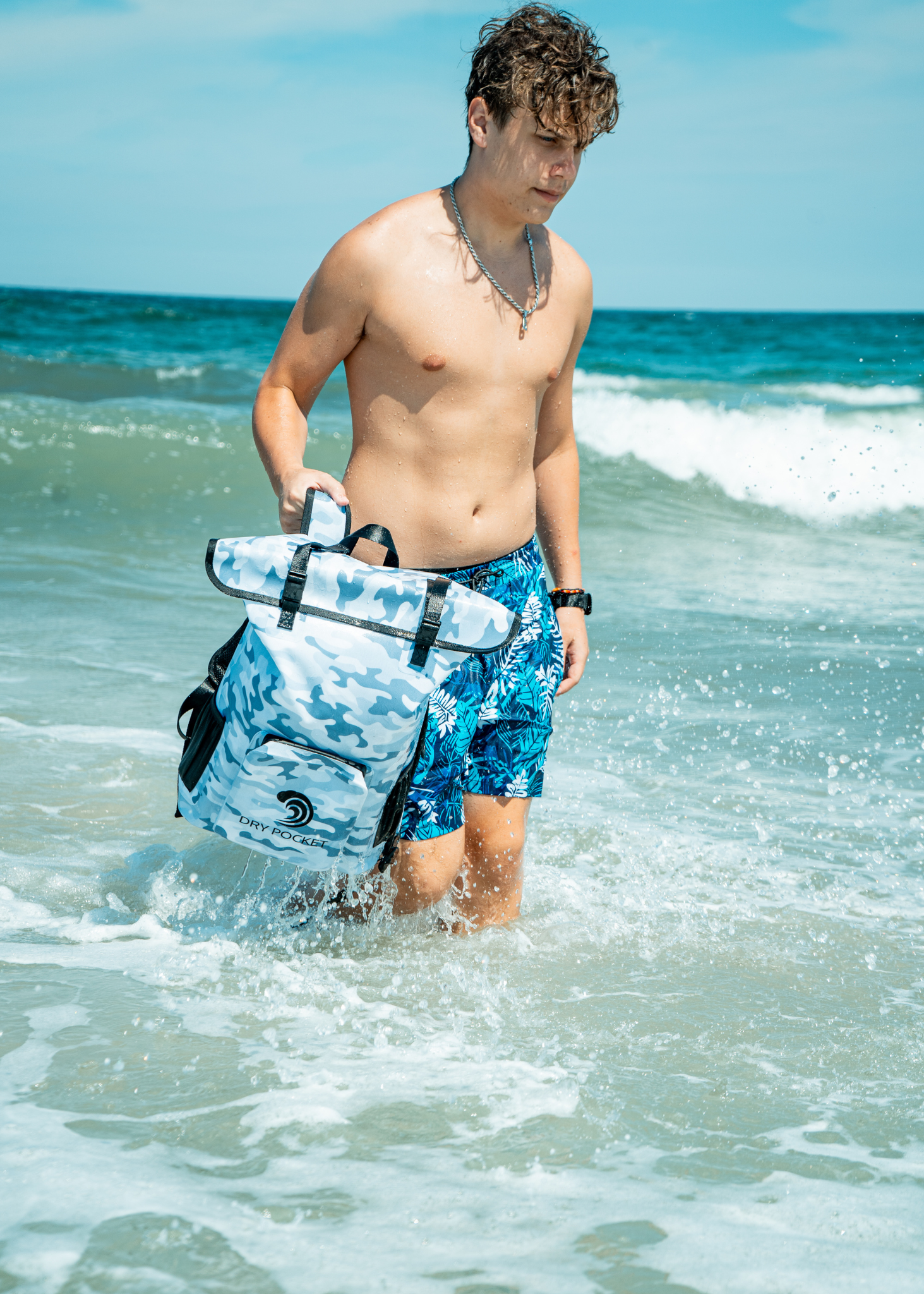 Man in blue swim trunks holding a surfboard in the ocean
