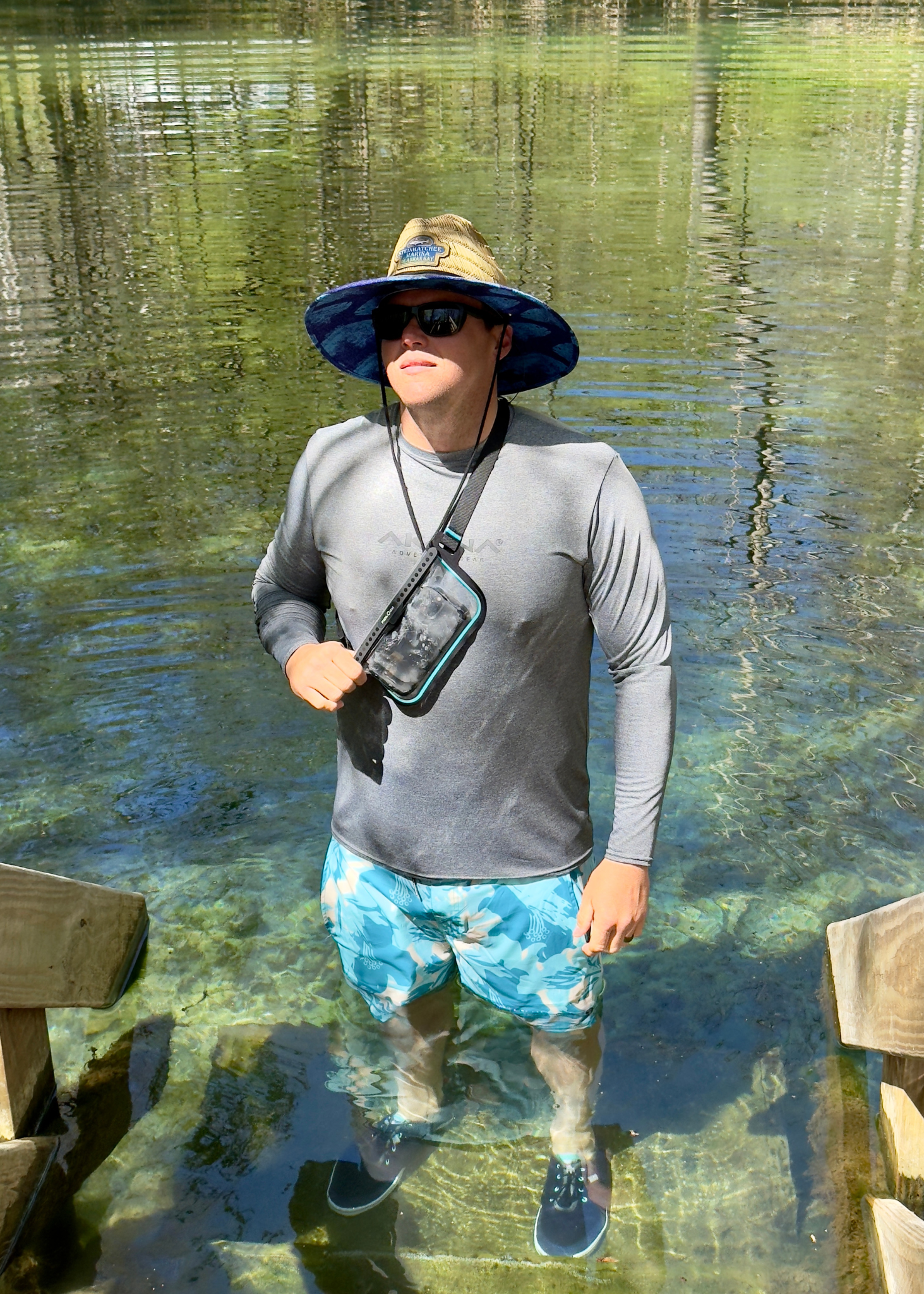 Person wearing a hat and sunglasses standing in clear water