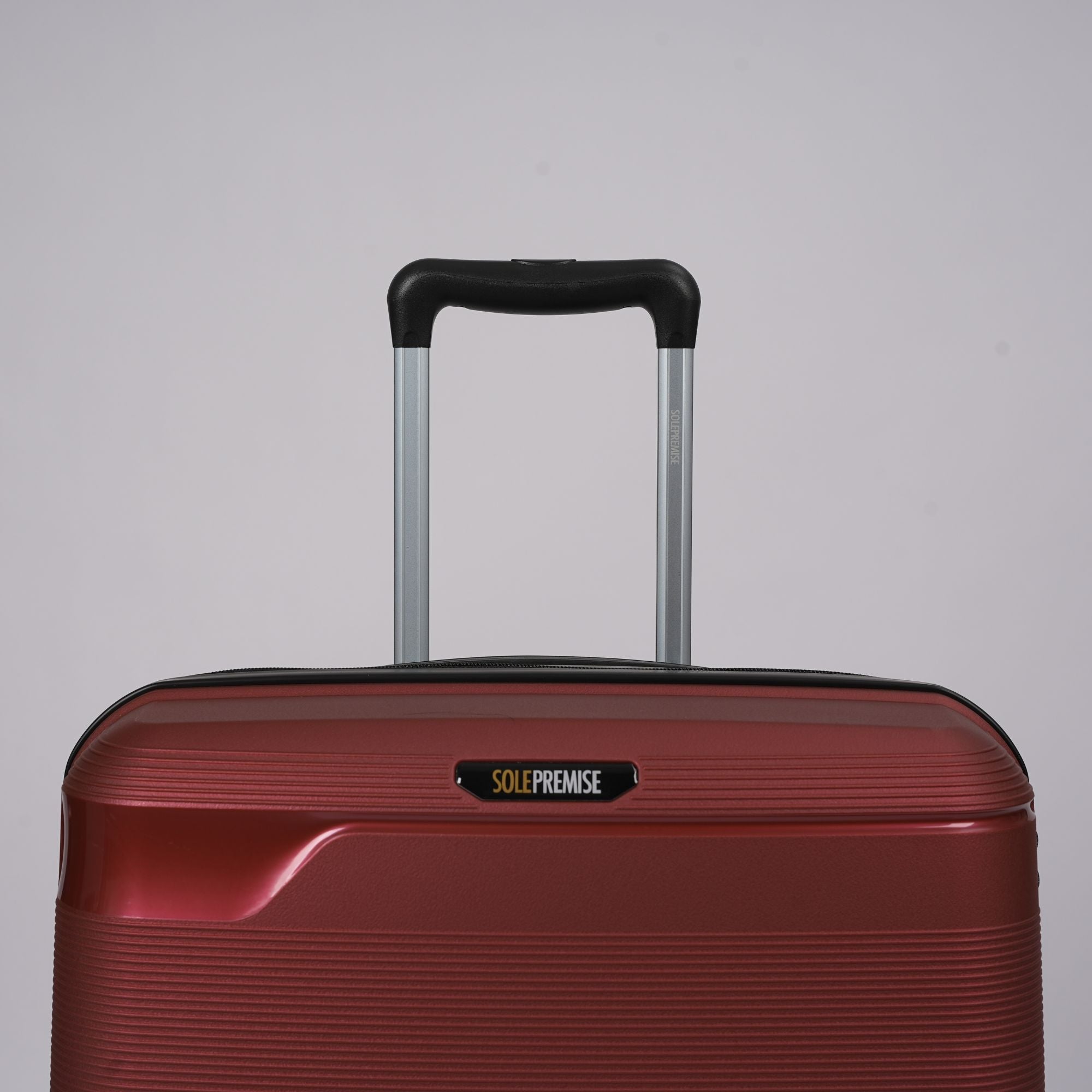 Red suitcase with a black handle on a gray background