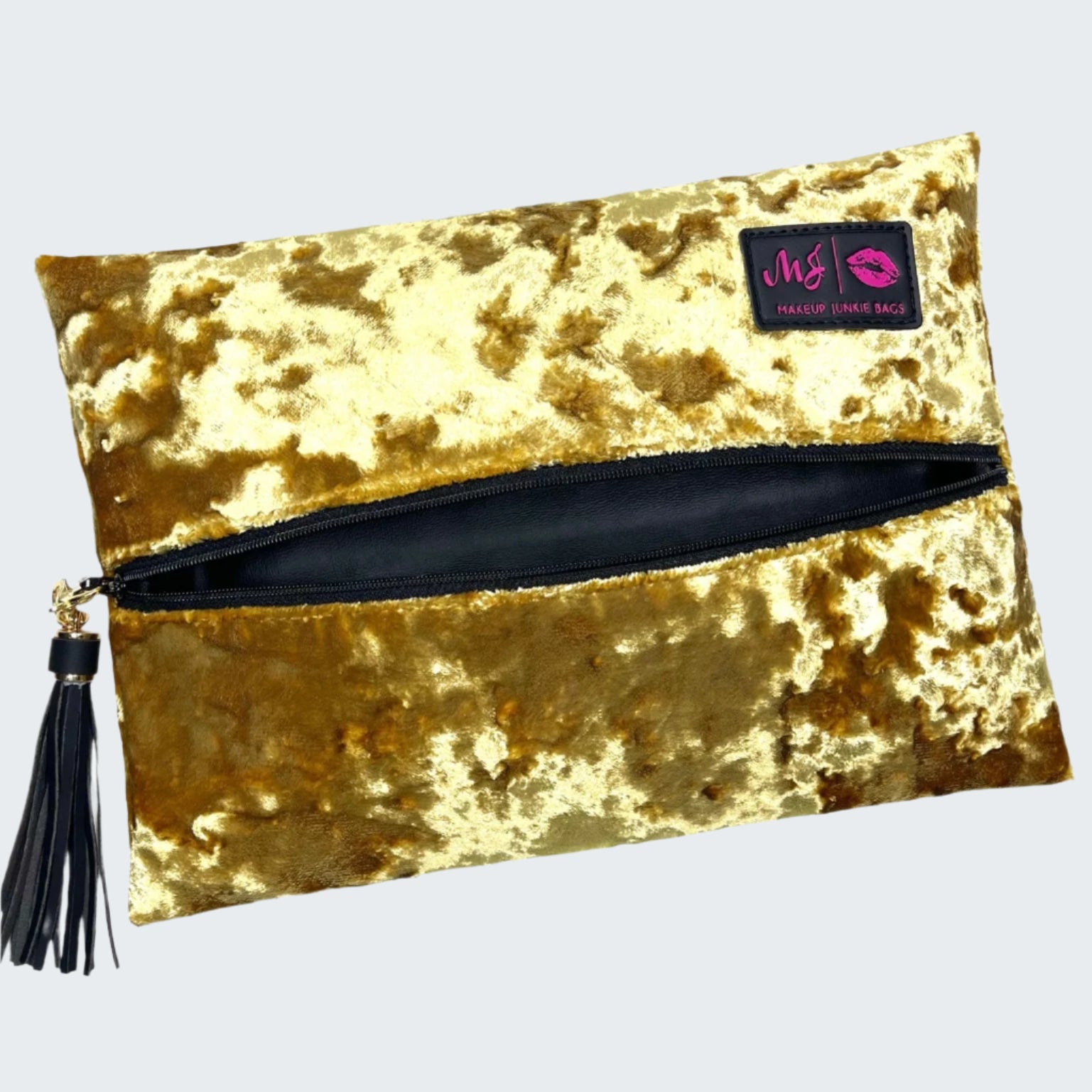 Gold velvet clutch bag with a black zipper and tassel on a white background