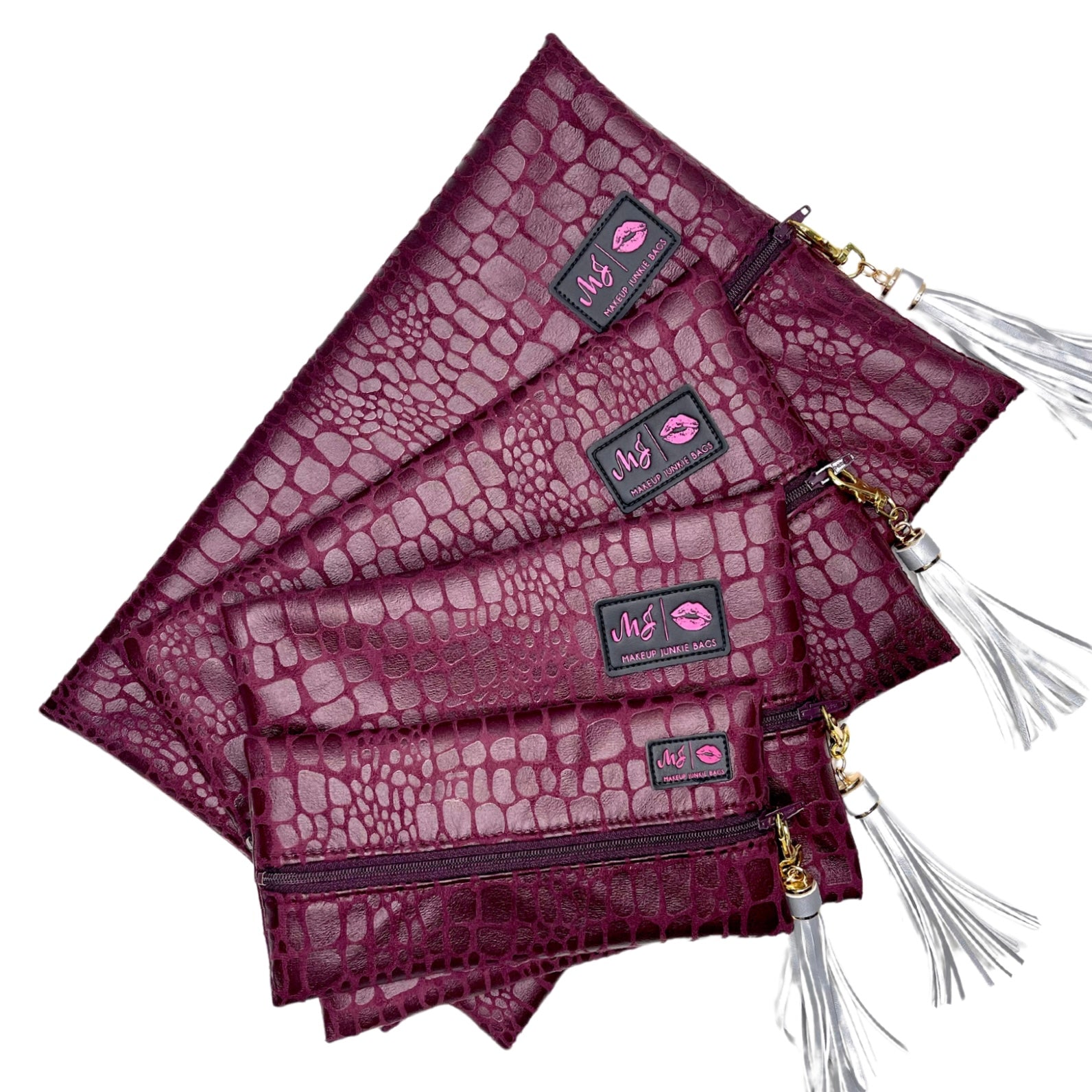 Set of purple crocodile-textured pouches with tassels on a white background