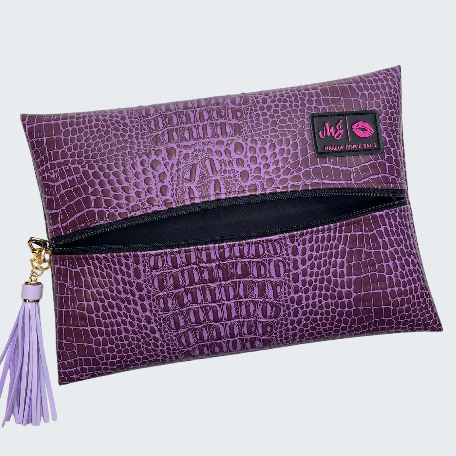 Purple crocodile-textured clutch bag with a tassel on a white background
