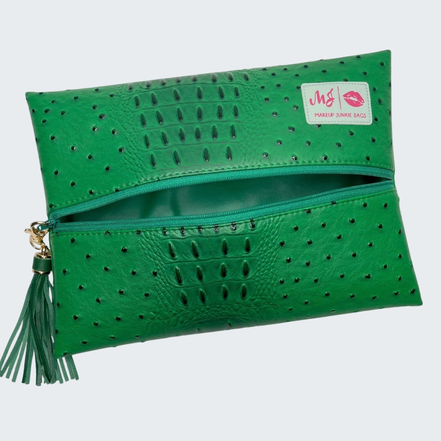Green clutch bag with perforated design and tassel on a white background