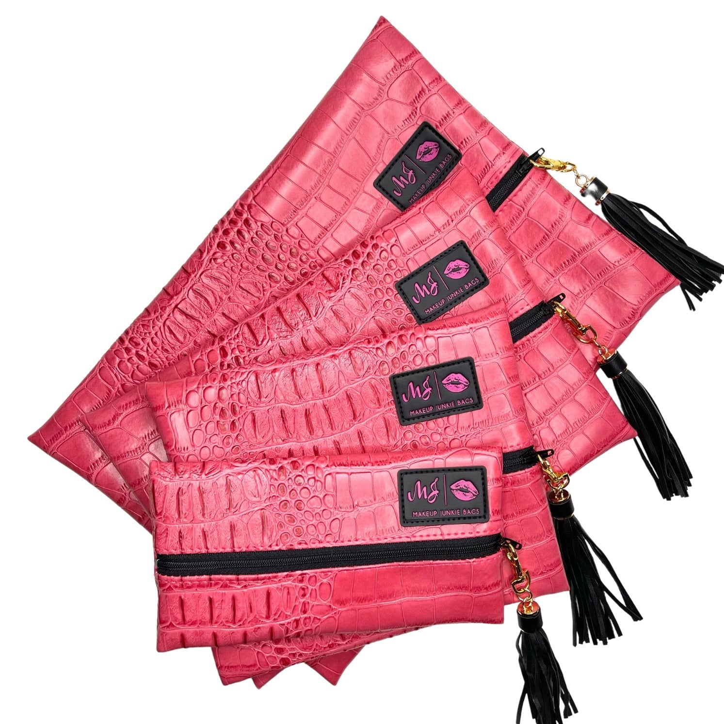 Set of pink crocodile-textured pouches with black zippers and tassels on a white background