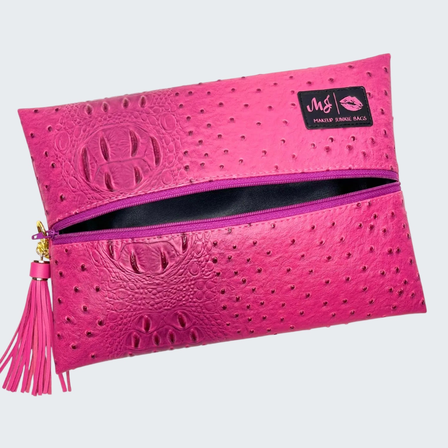 Pink makeup bag with embossed design and tassel on a white background