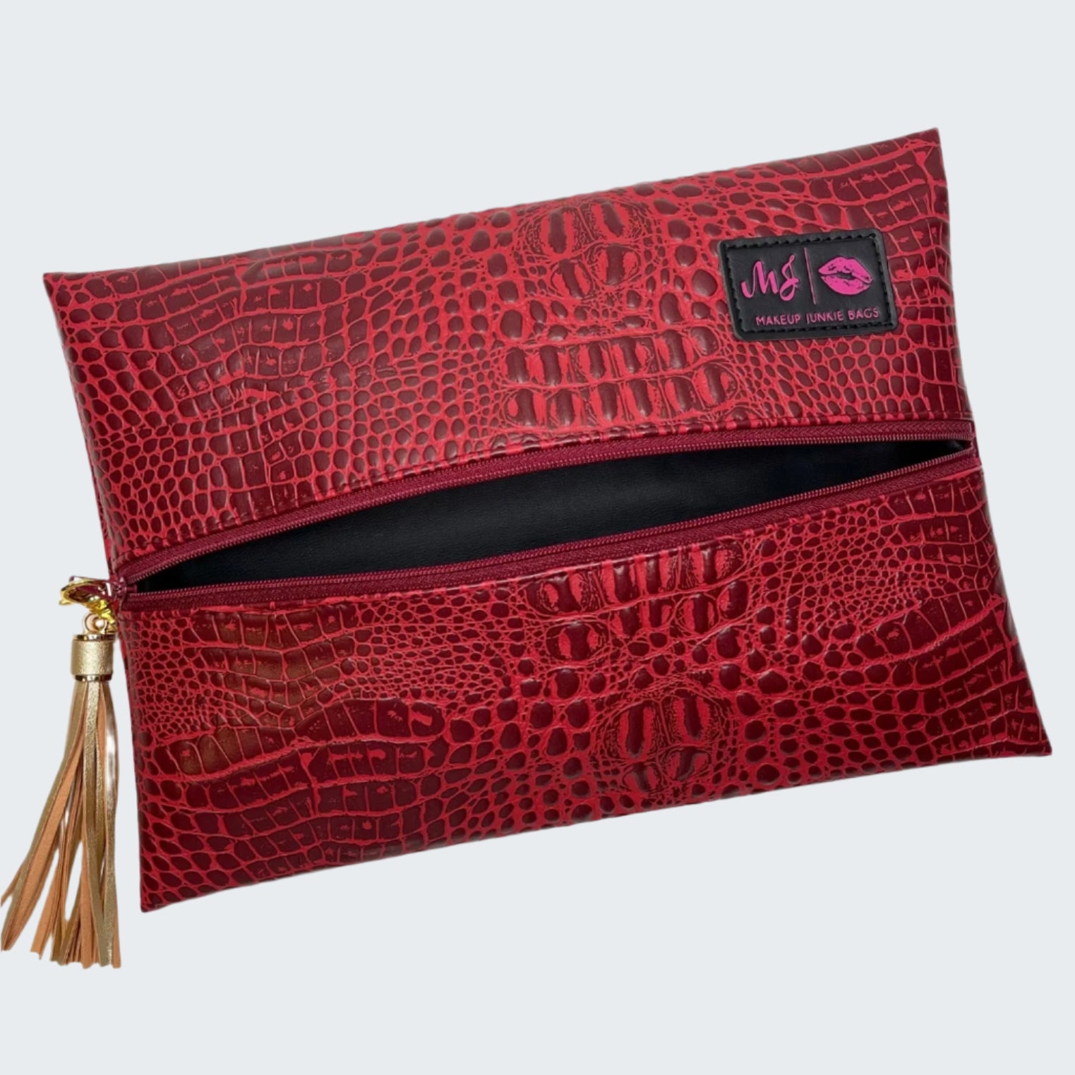 Red crocodile-patterned makeup bag with a tassel on a white background