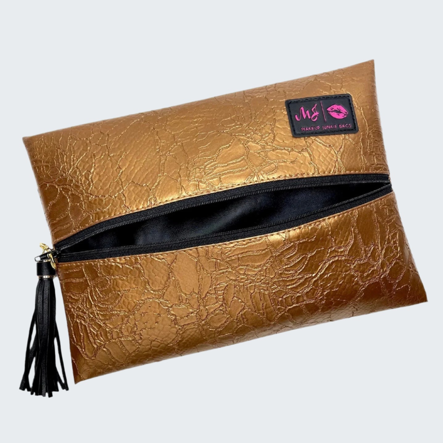 Gold clutch bag with a black tassel and visible brand logo on a white background