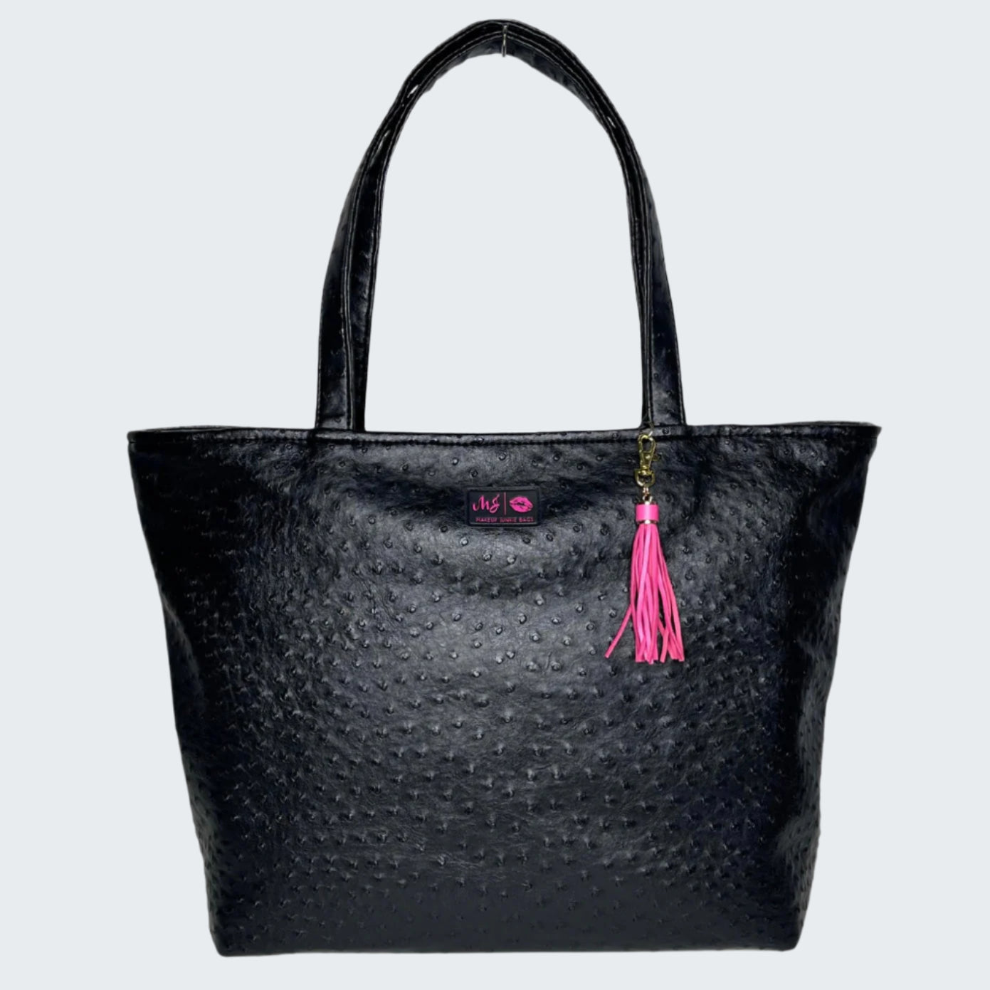Black textured tote bag with a pink tassel on a white background