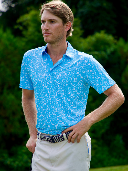 Man wearing a blue patterned polo shirt and white pants outdoors.