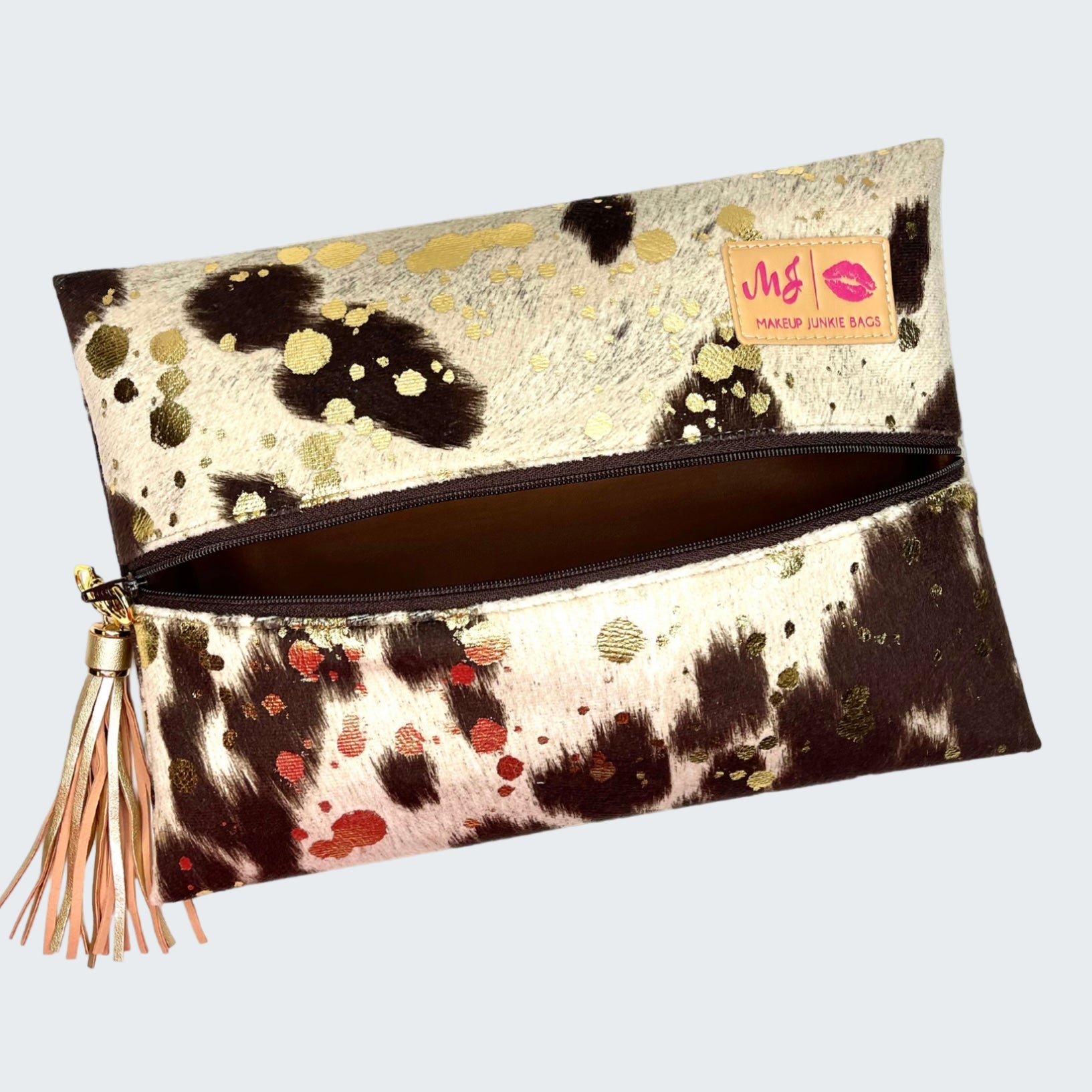 Clutch bag with cow print pattern and tassel on a white background