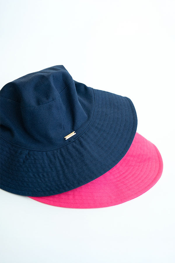 Navy and pink bucket hats stacked on a white background
