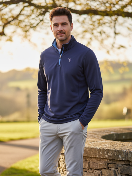 Man wearing a navy blue pullover with a logo in a park setting