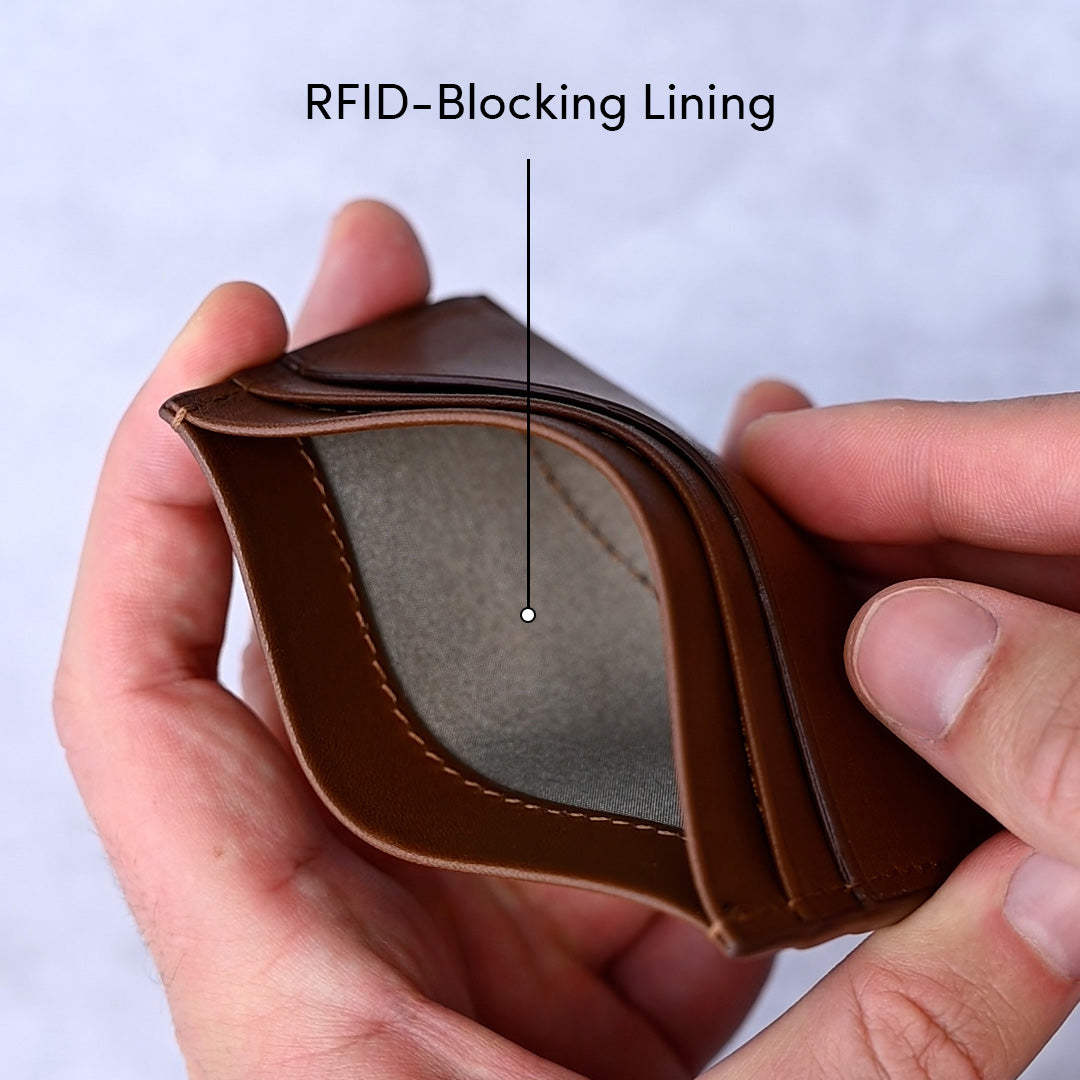 Brown wallet with an RFID-blocking lining held by a hand against a light blue background