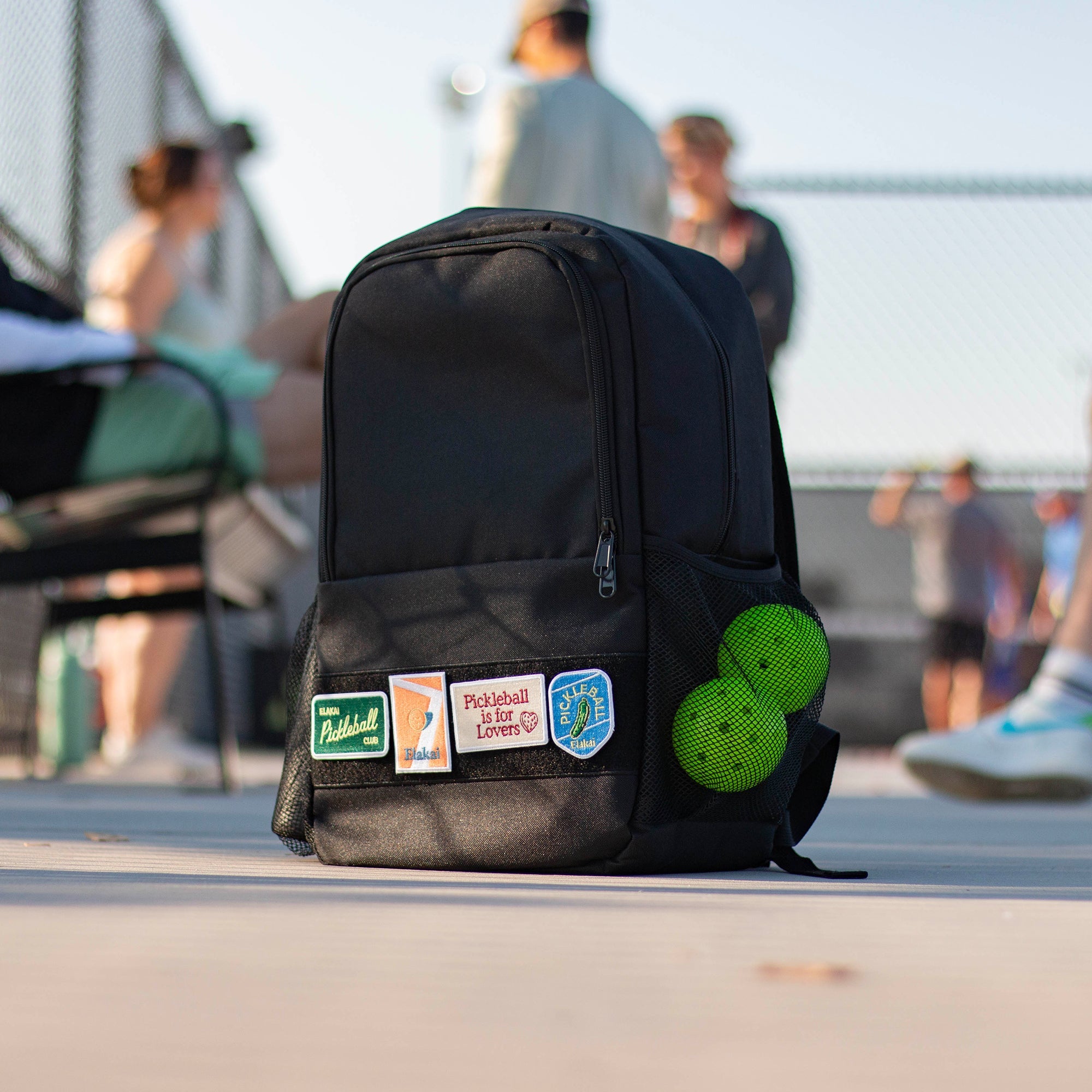 Black backpack with stickers on a tennis court